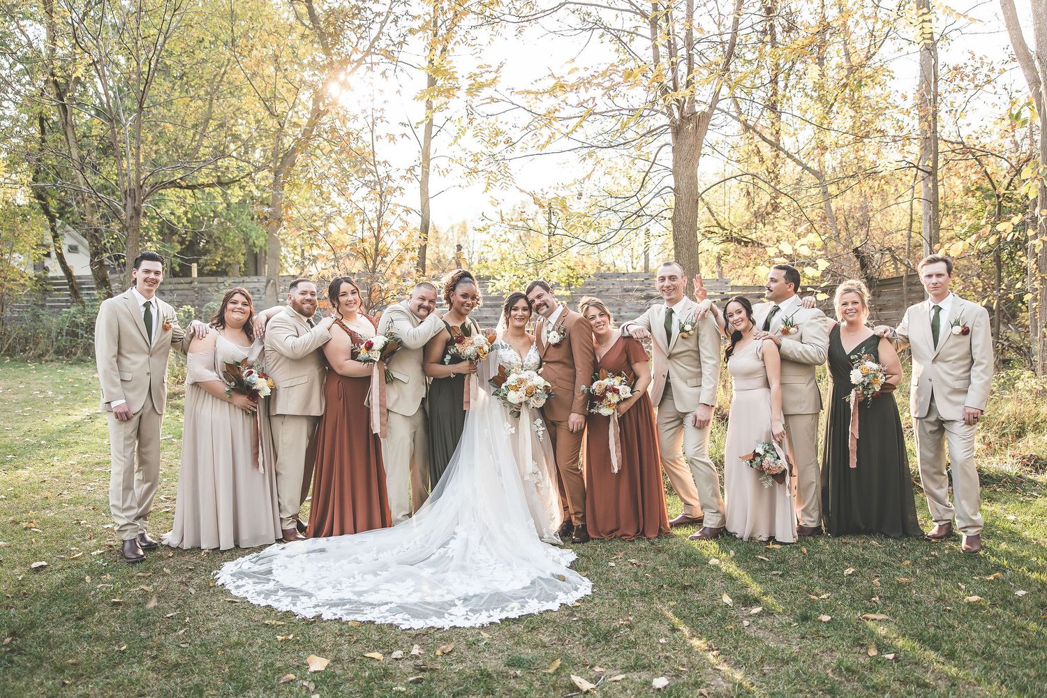 Wedding group photo in natural outdoor setting with fall colors and evening light.