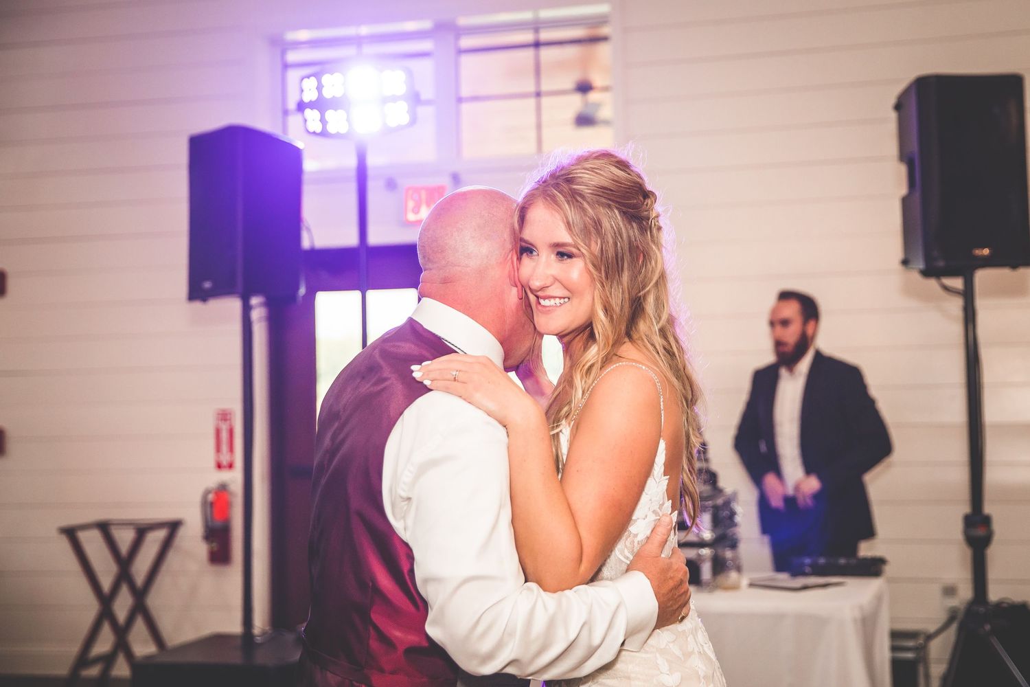 Romantic dance scene with purple mood lighting at indoor wedding reception.