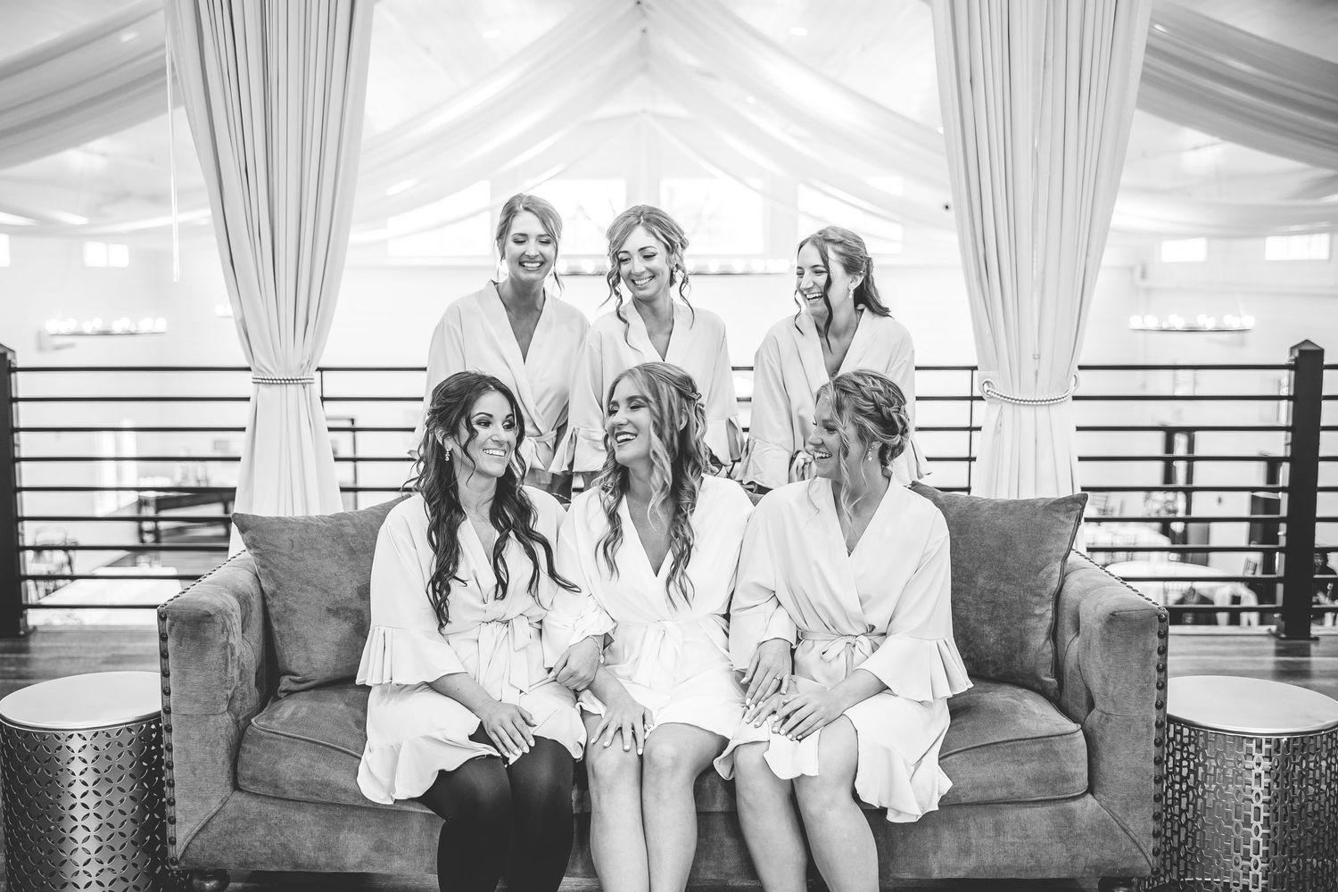 Interior of bright white wedding venue with draped fabric and seating area.