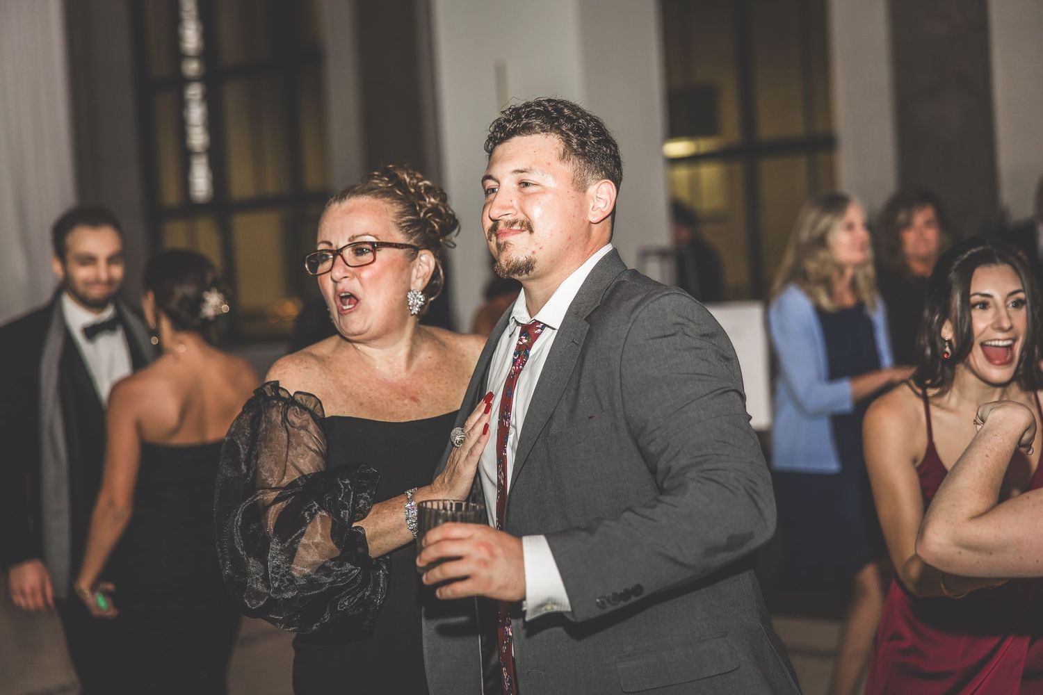Guests enjoying themselves on the dance floor at an elegant indoor wedding reception.