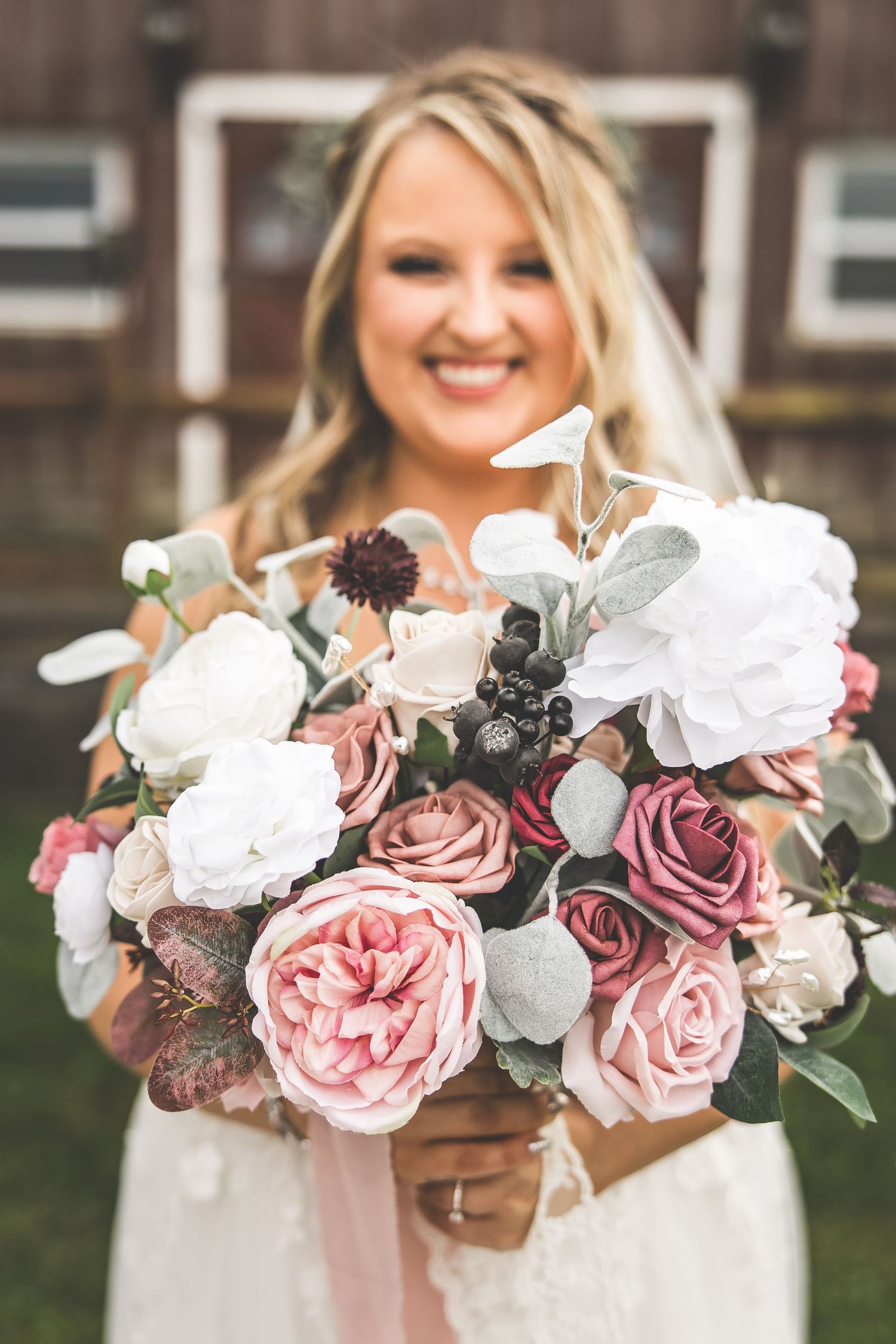 Beautiful bridal bouquet featuring pink and mauve roses with white flowers and greenery against a blurred background.