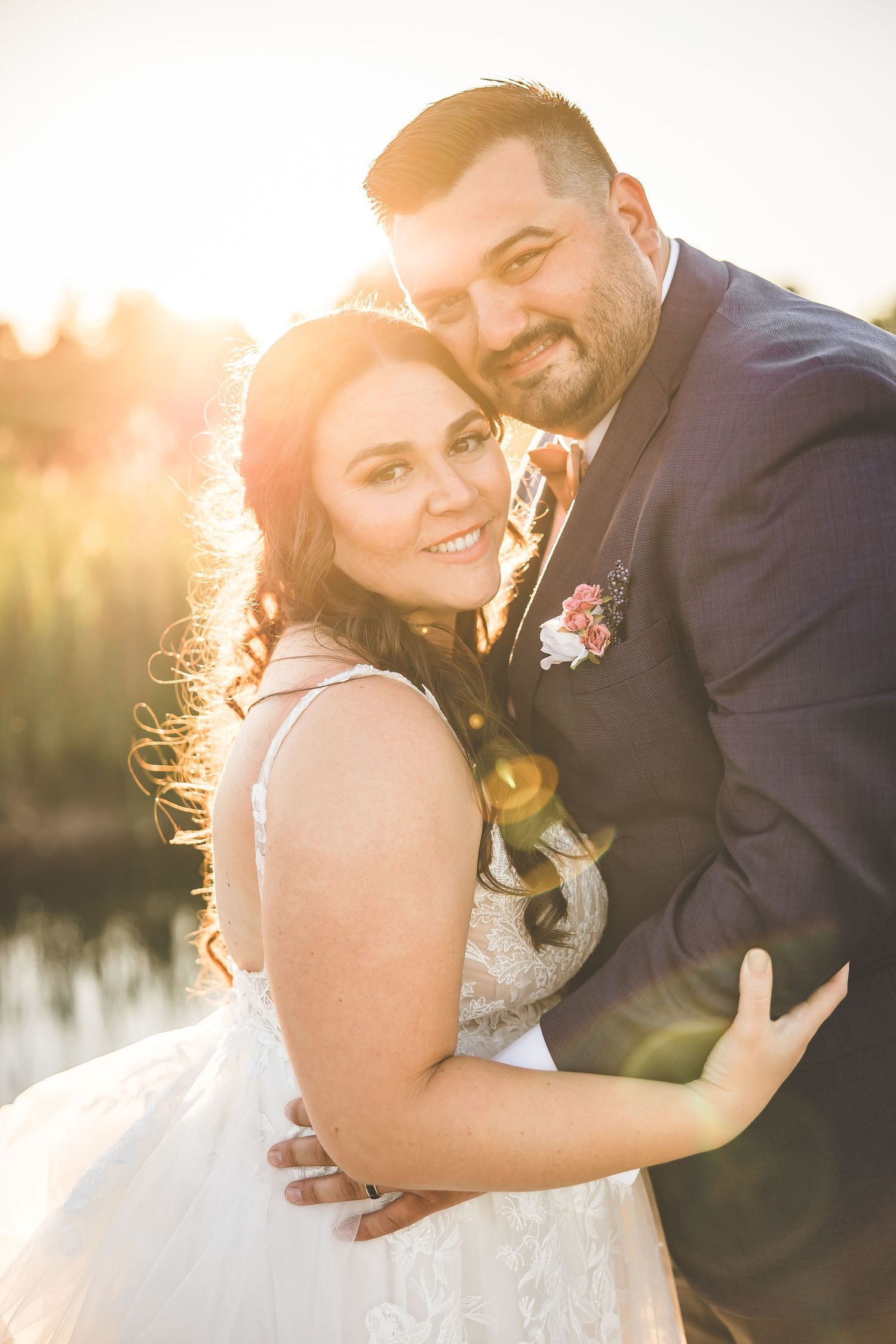 Newlyweds share intimate moments during golden hour photography session by a lake.