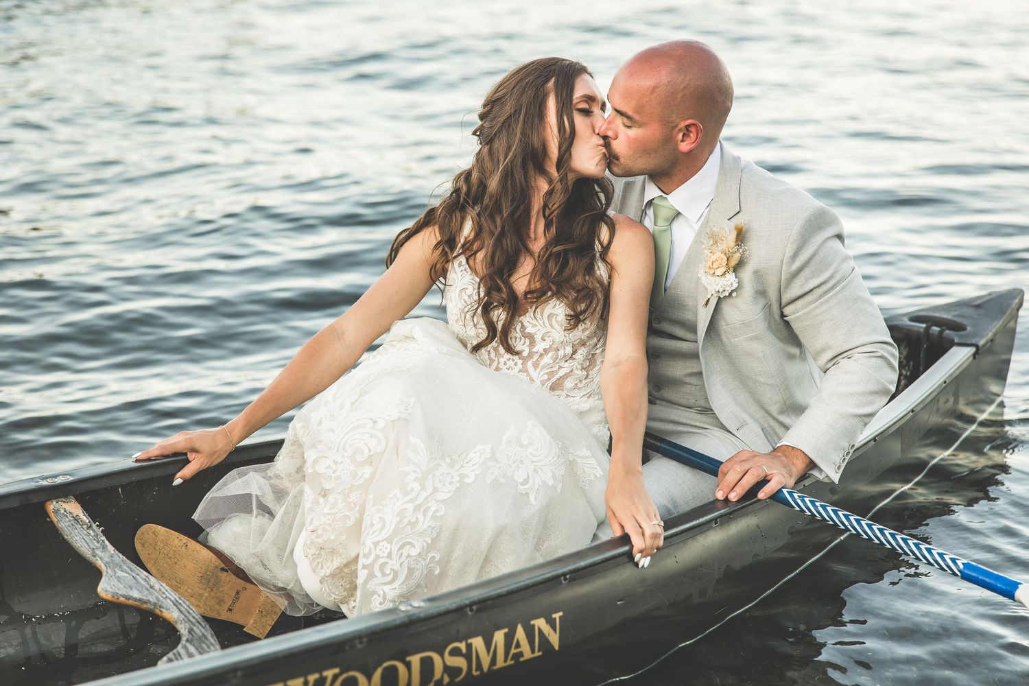 Newlyweds sharing an intimate moment in a wooden boat on the water.