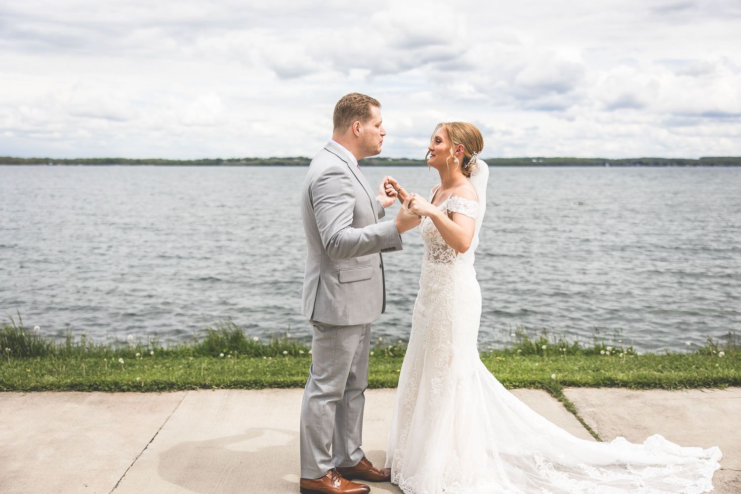 Joyful wedding couple sharing emotional first look by waterside.