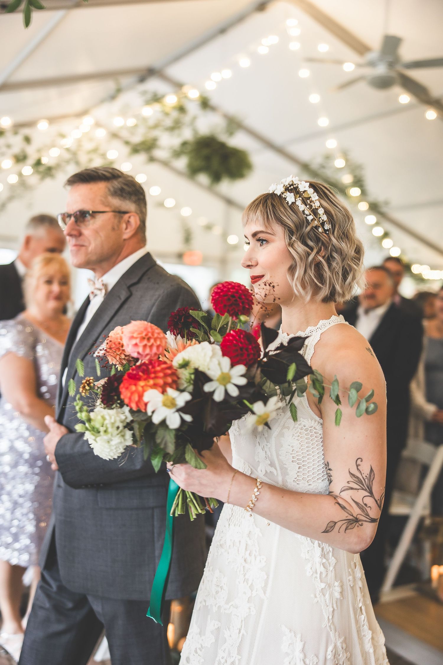 Wedding ceremony participants hold beautiful bouquets with red and white flowers.