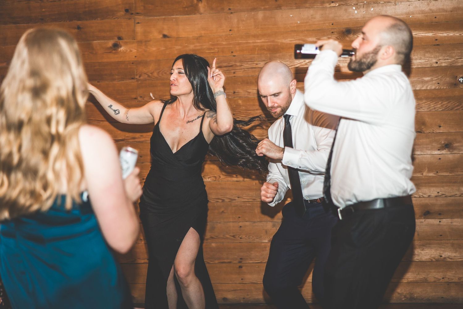 Wedding reception guests dancing and celebrating in a rustic wooden barn venue.