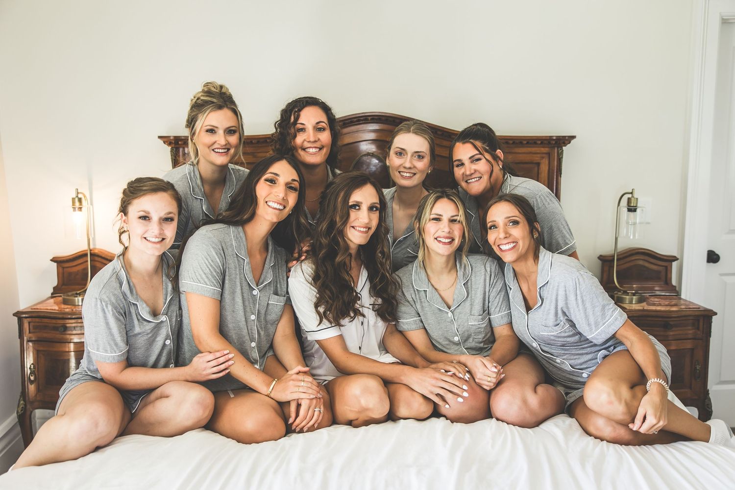 Wedding party lounging together on bed wearing matching grey outfits.