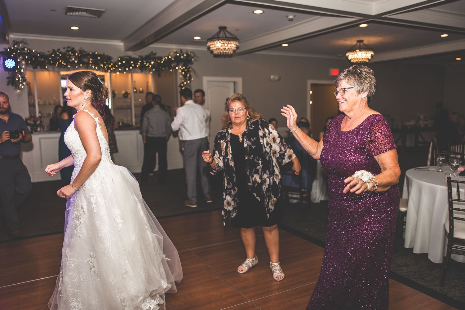 Wedding reception venue with dance floor and decorative string lights overhead.