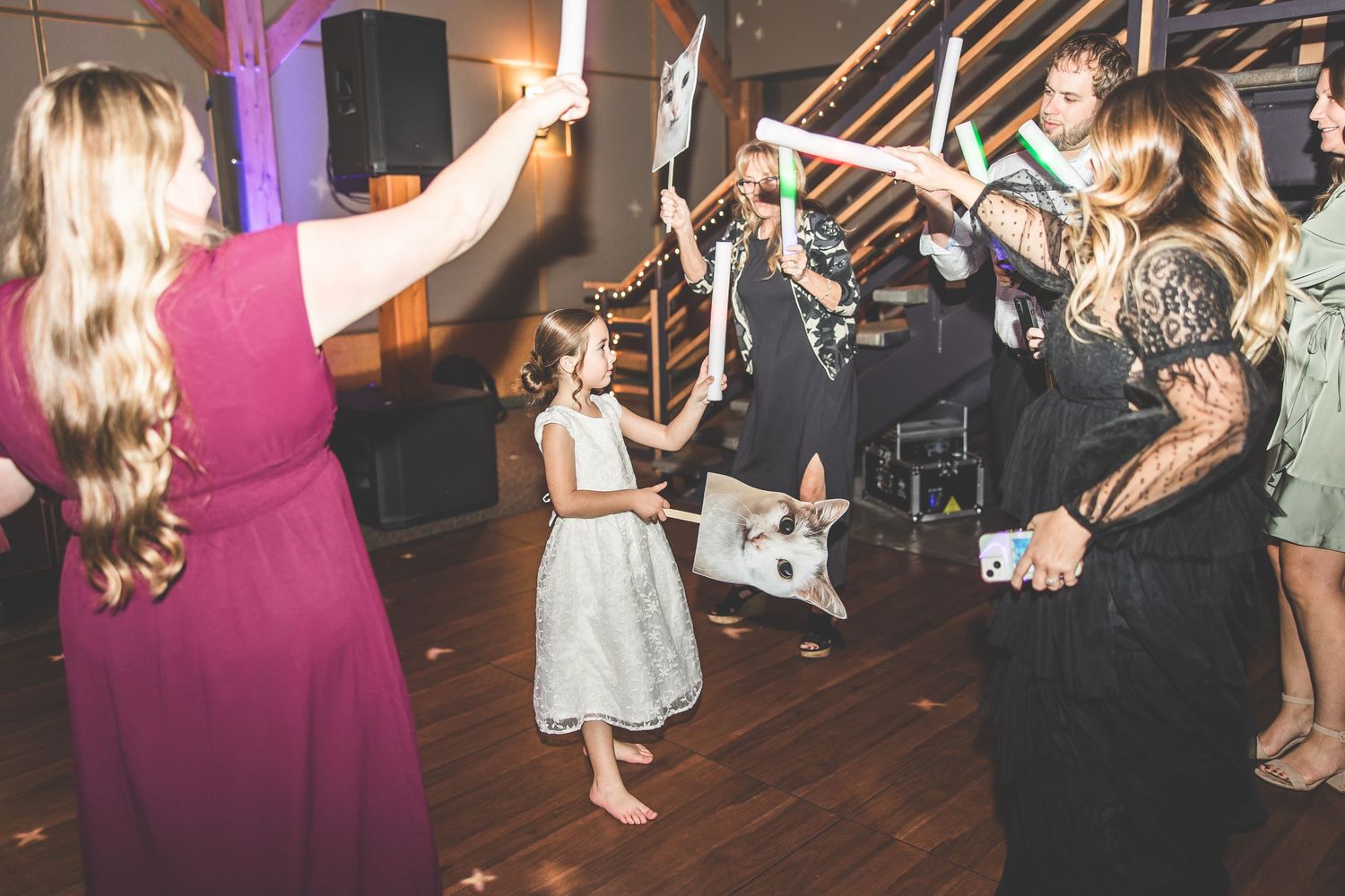 Wedding guests dancing and celebrating on a dimly lit dance floor with purple accents.