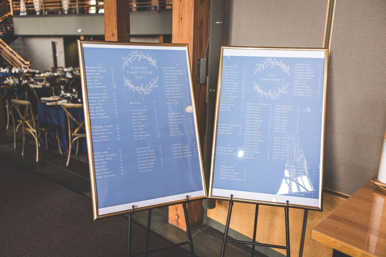Two blue and white seating chart displays on easels at wedding venue.