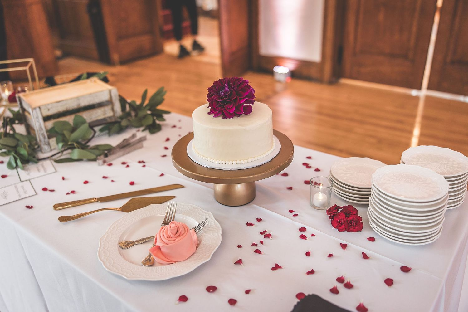 Elegant table settings with rose petals and floral centerpieces at wedding reception.
