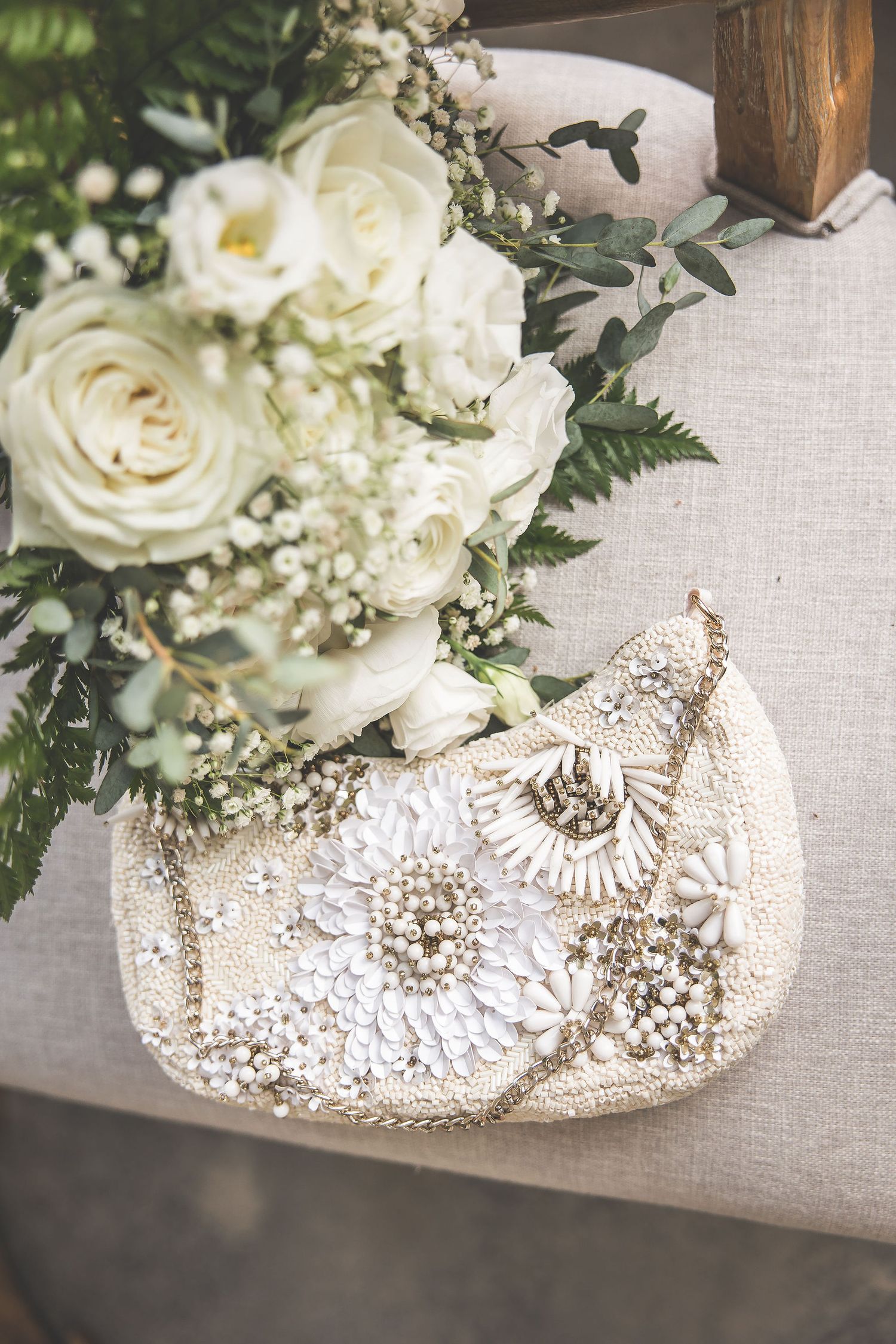 Ornate beaded bridal shoes displayed with white roses and delicate floral arrangements.