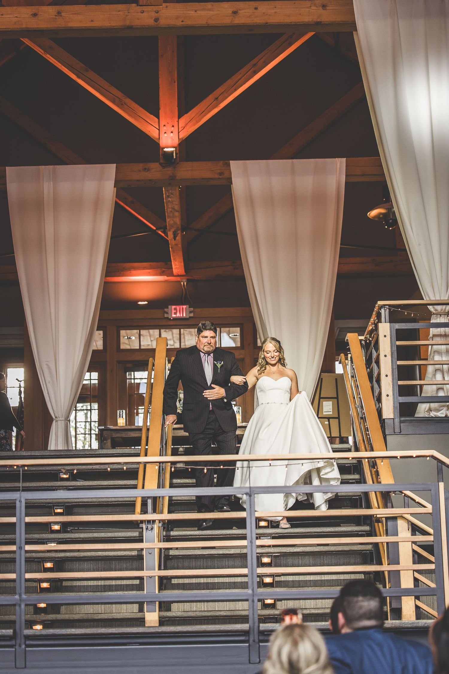 Elegant wedding ceremony setup with white drapes and exposed wooden beams in a modern industrial venue.
