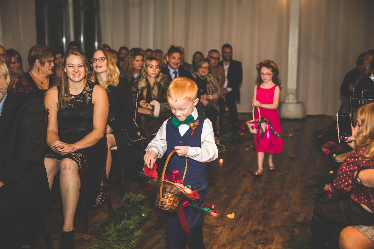 Wedding reception guests dancing and celebrating on a wooden dance floor under ambient lighting.