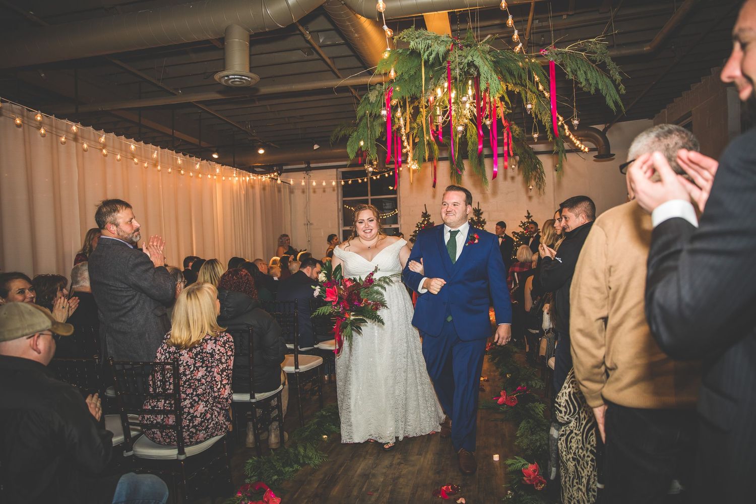 Wedding reception venue decorated with string lights and holiday decor as guests mingle.