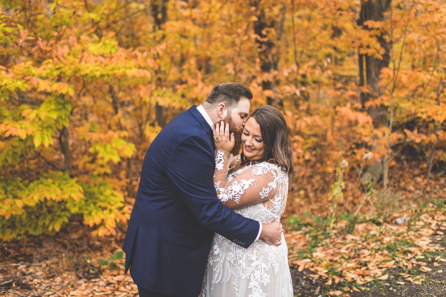 Romantic wedding moments captured against vibrant fall foliage background.