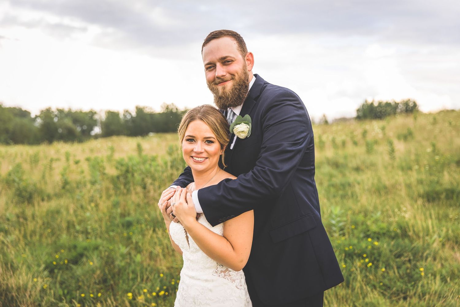 Wedding couple shares intimate moments during their outdoor photo session in a grassy field.