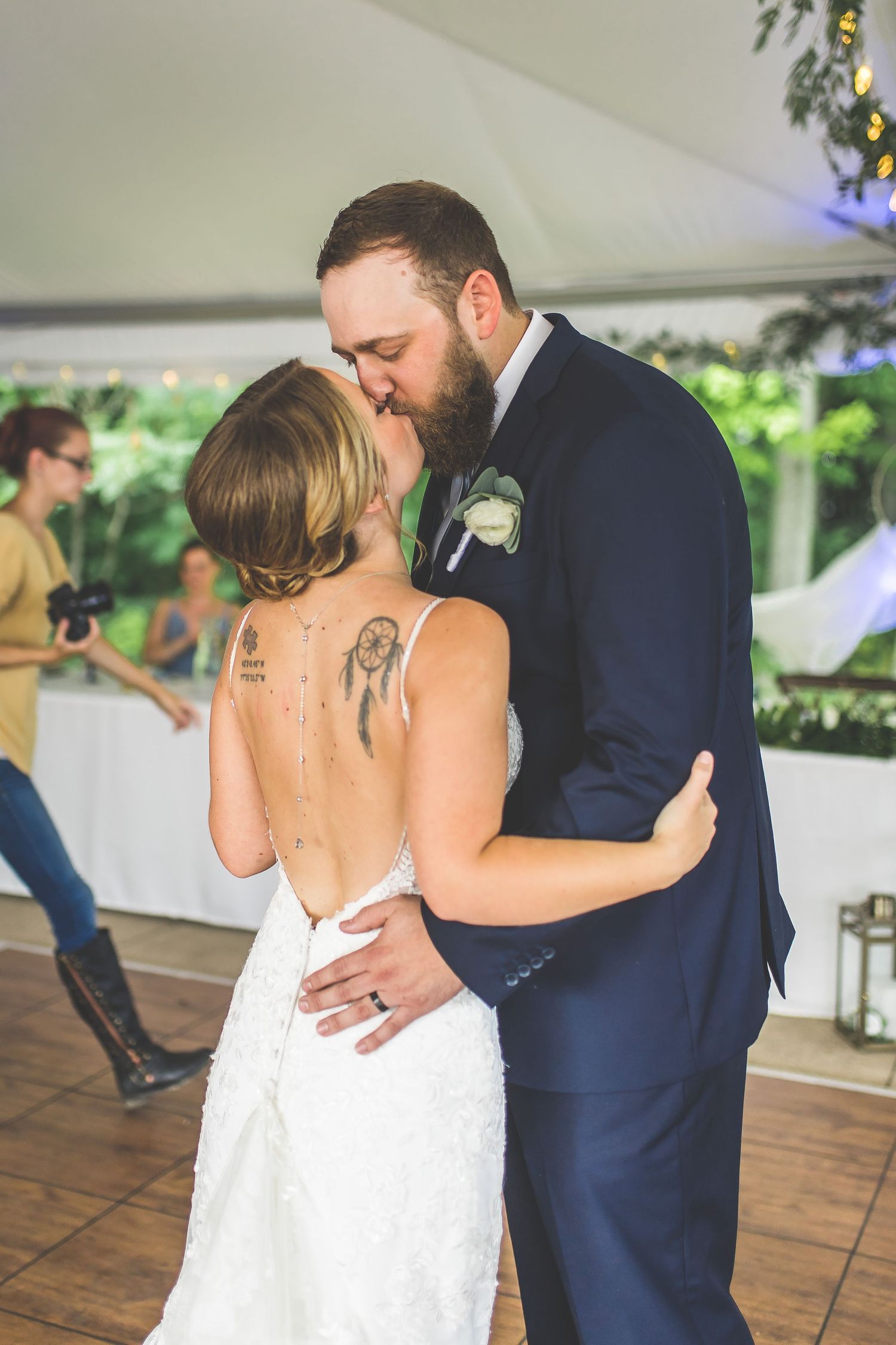 Couple embraces during their wedding dance on wooden flooring under a white tent canopy.