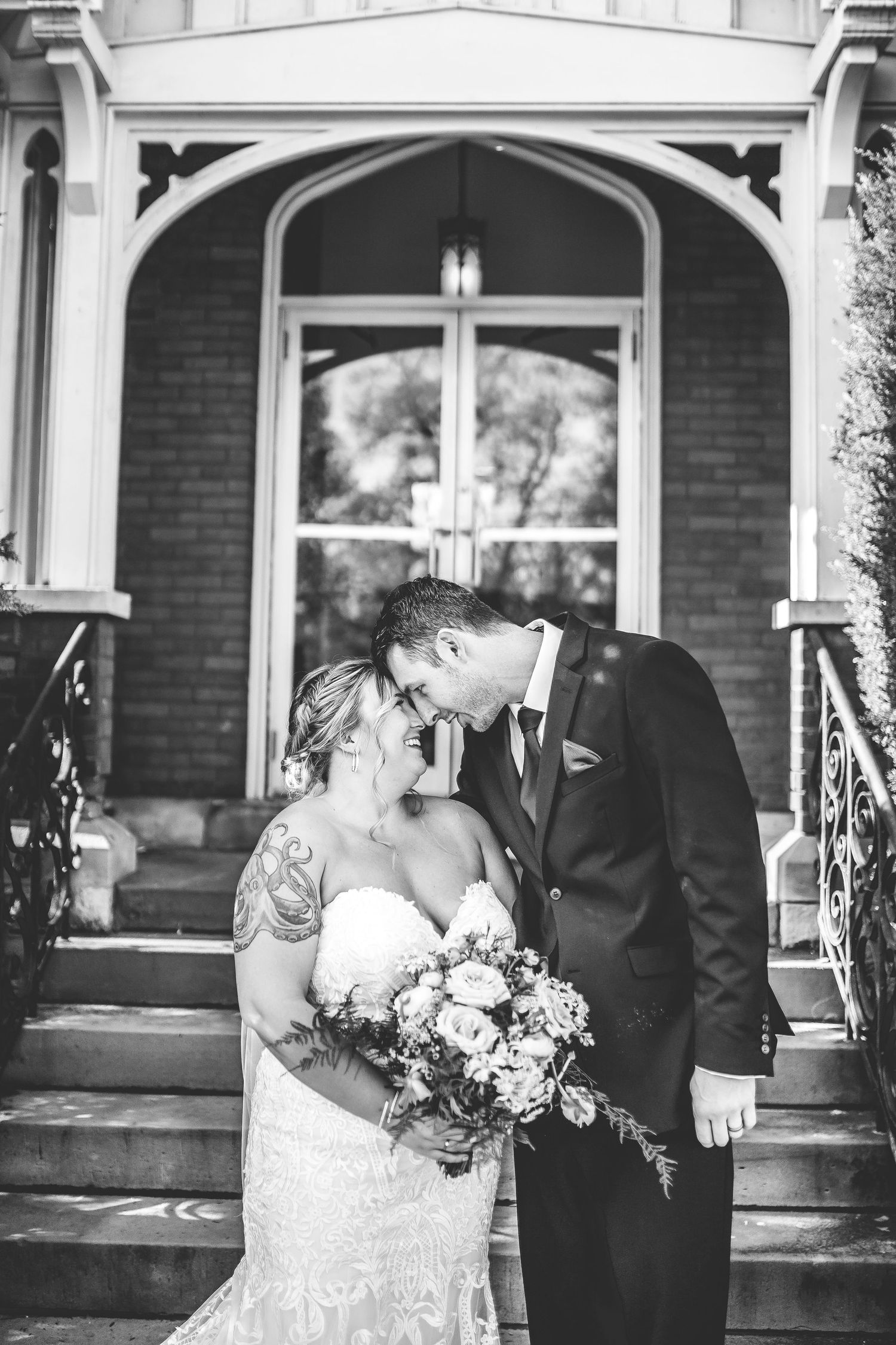 Black and white wedding portraits showcase romantic moments under church archway.
