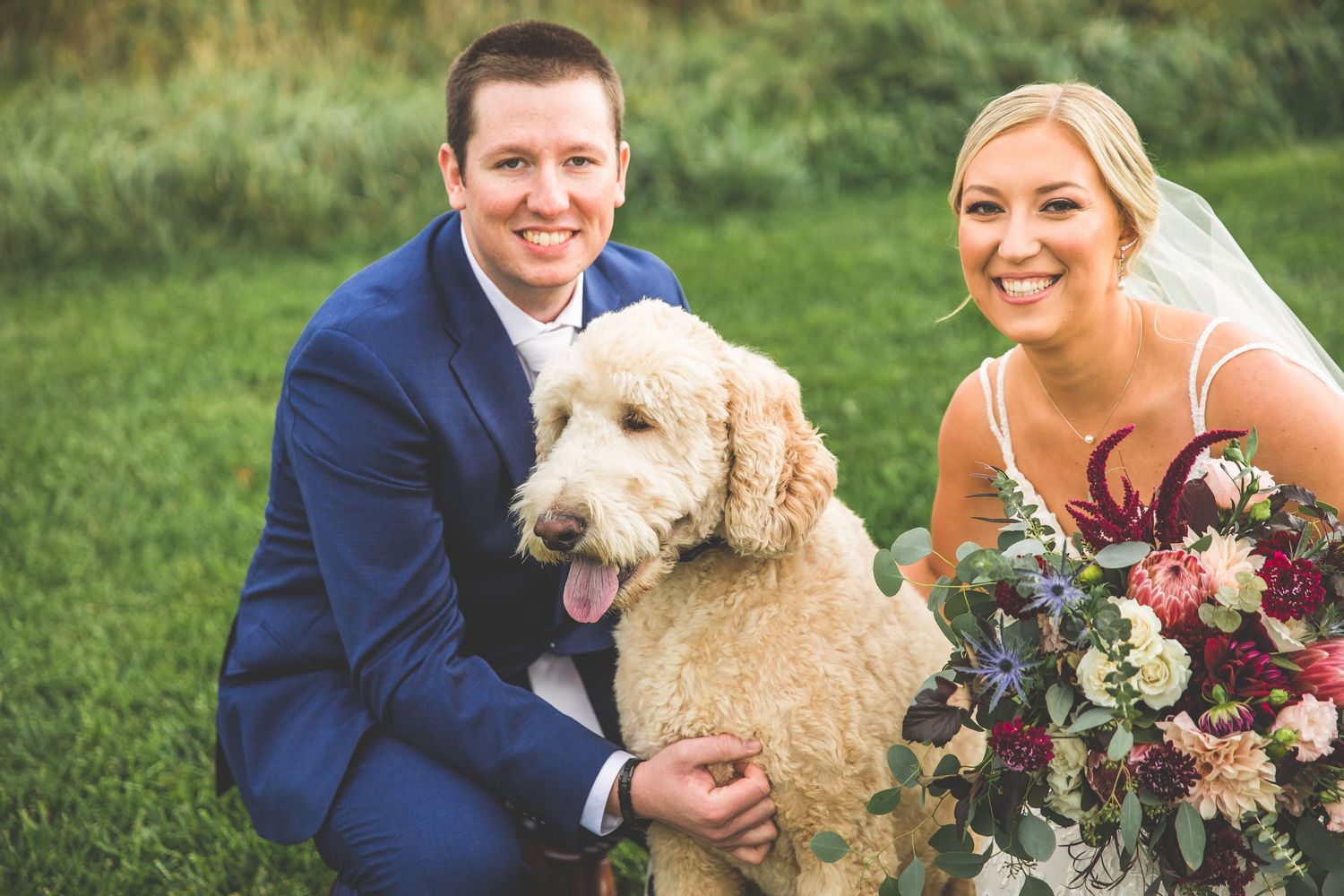 Wedding couple poses with their fluffy white dog during outdoor photo session.