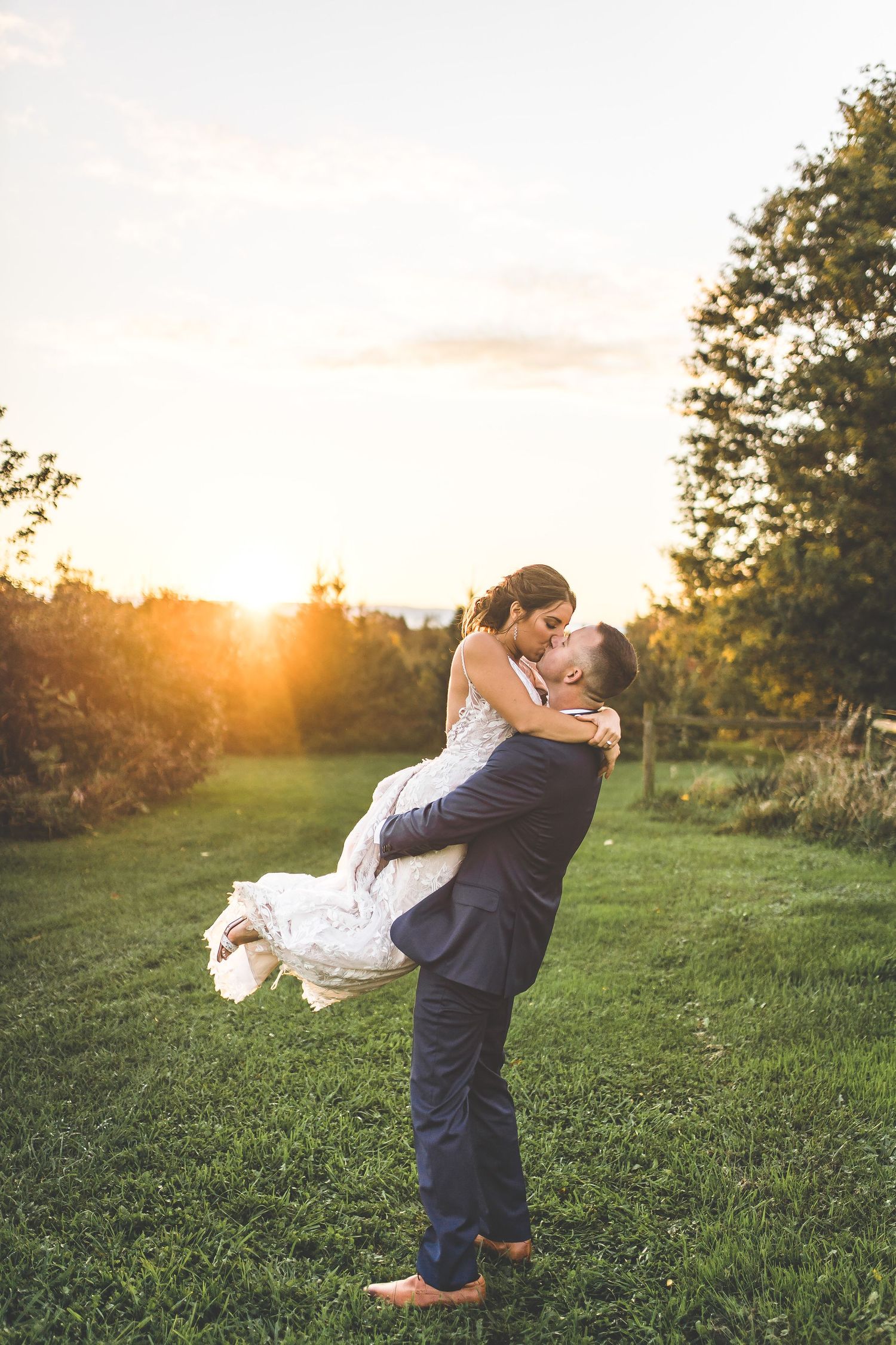 Couple shares romantic sunset moments in field with dramatic lighting and playful poses.