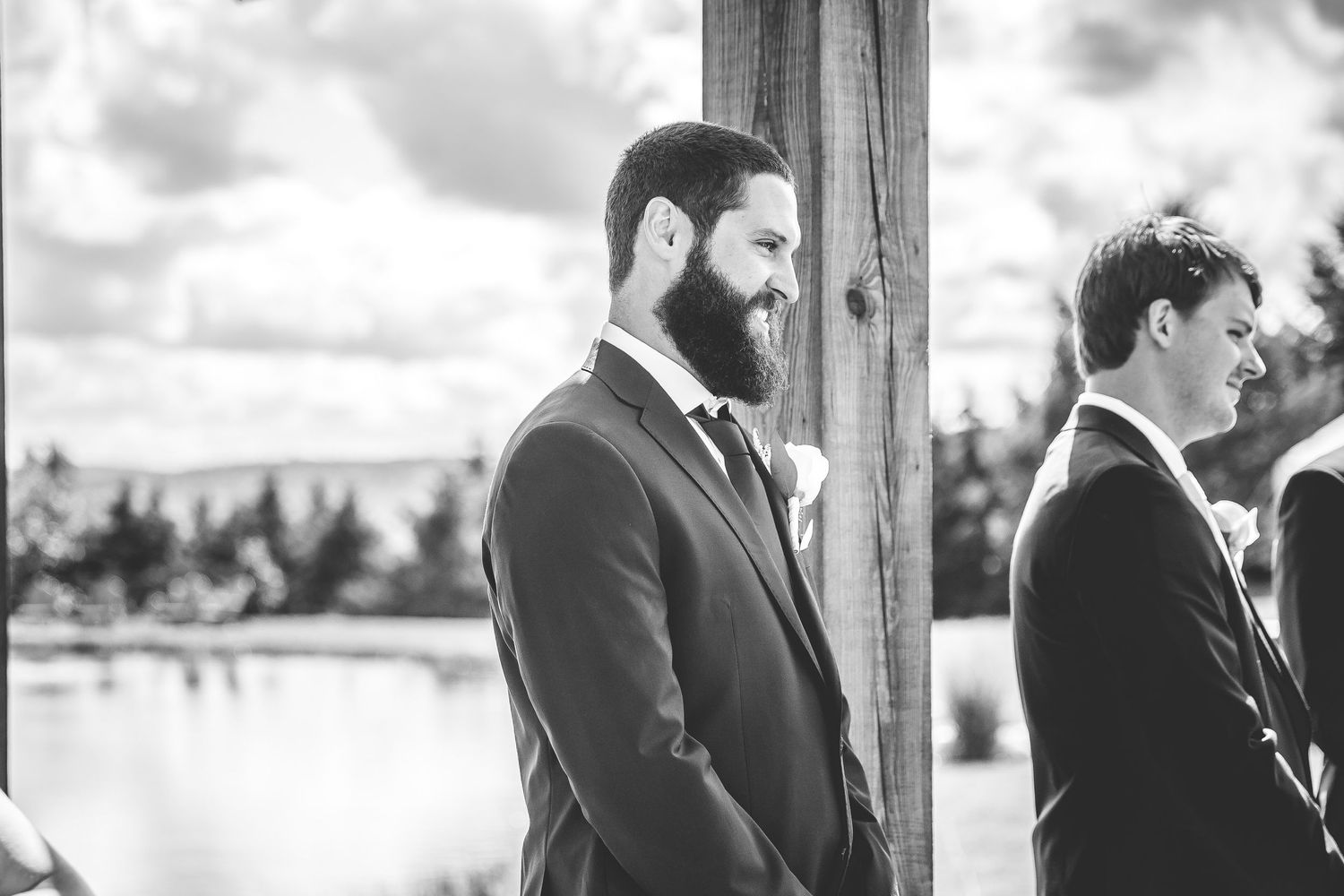Black and white photo of groomsmen standing at an outdoor wedding ceremony with mountain views.