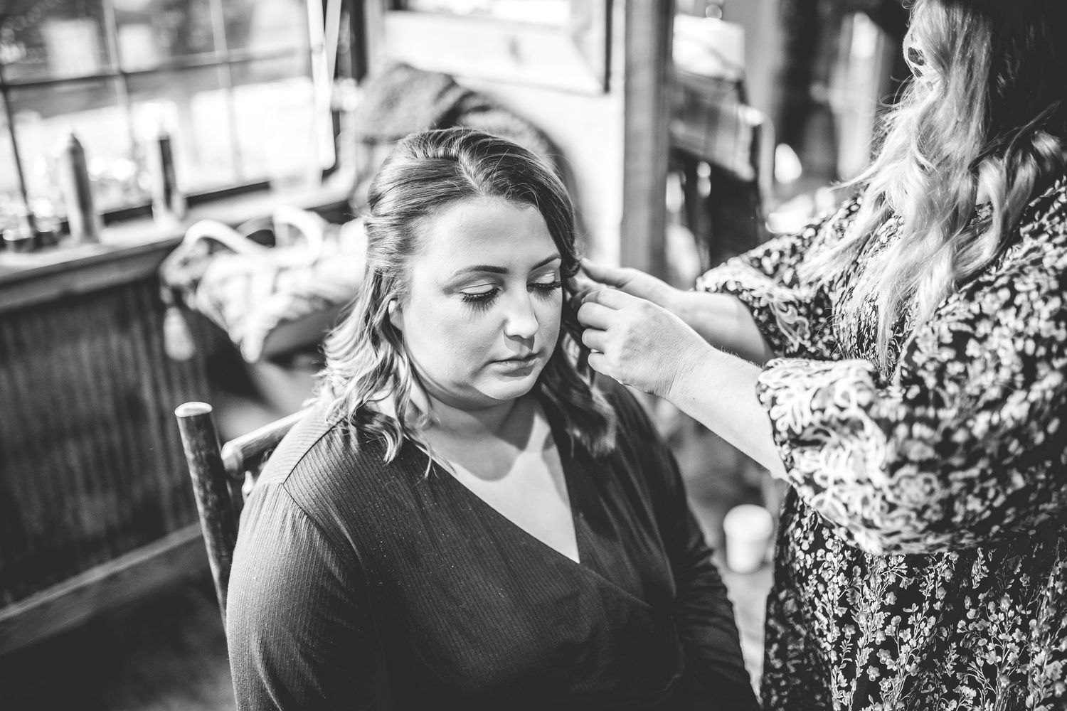 Black and white image of wedding preparation with styling taking place indoors.