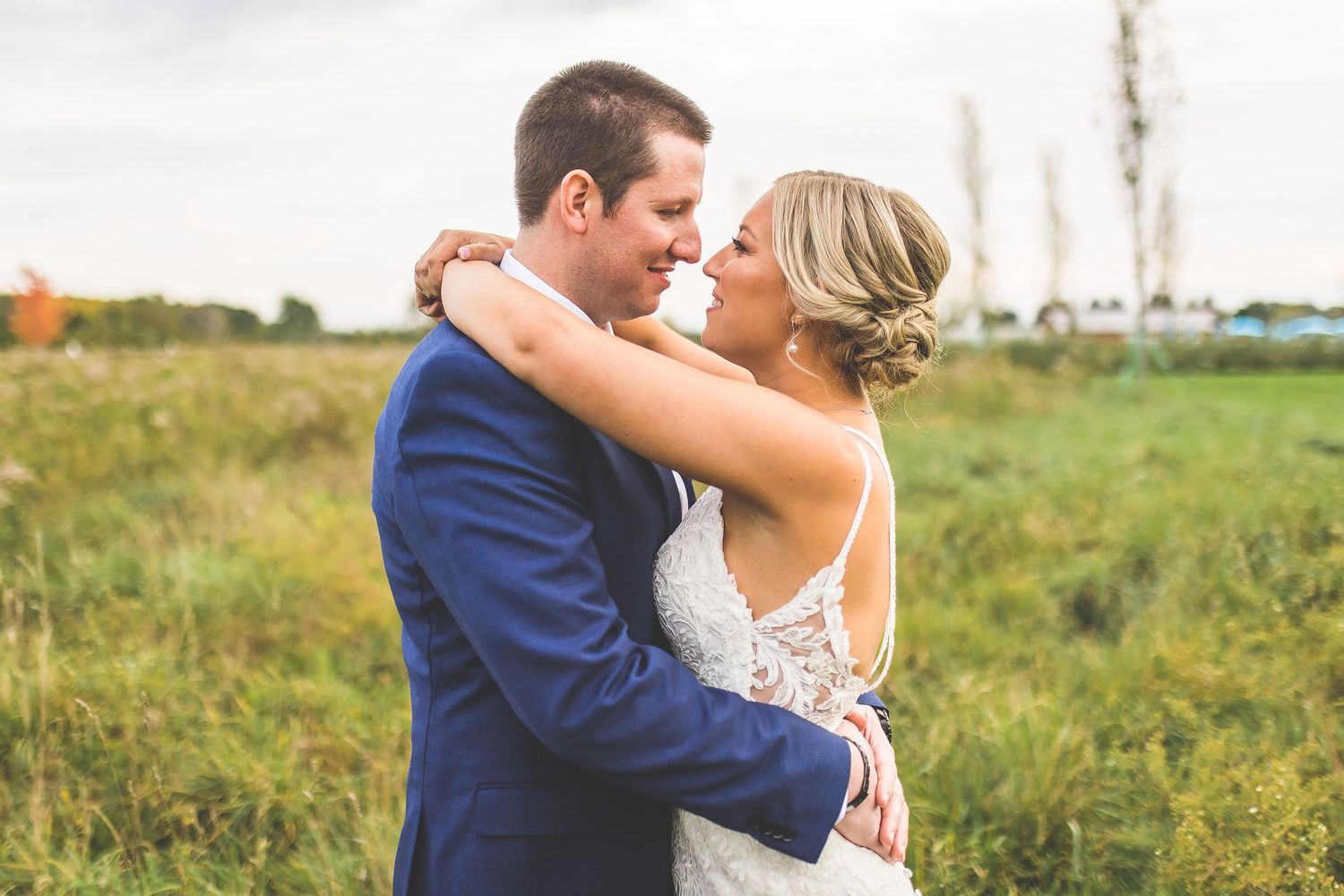 Newlyweds pose together in an outdoor field with natural lighting.
