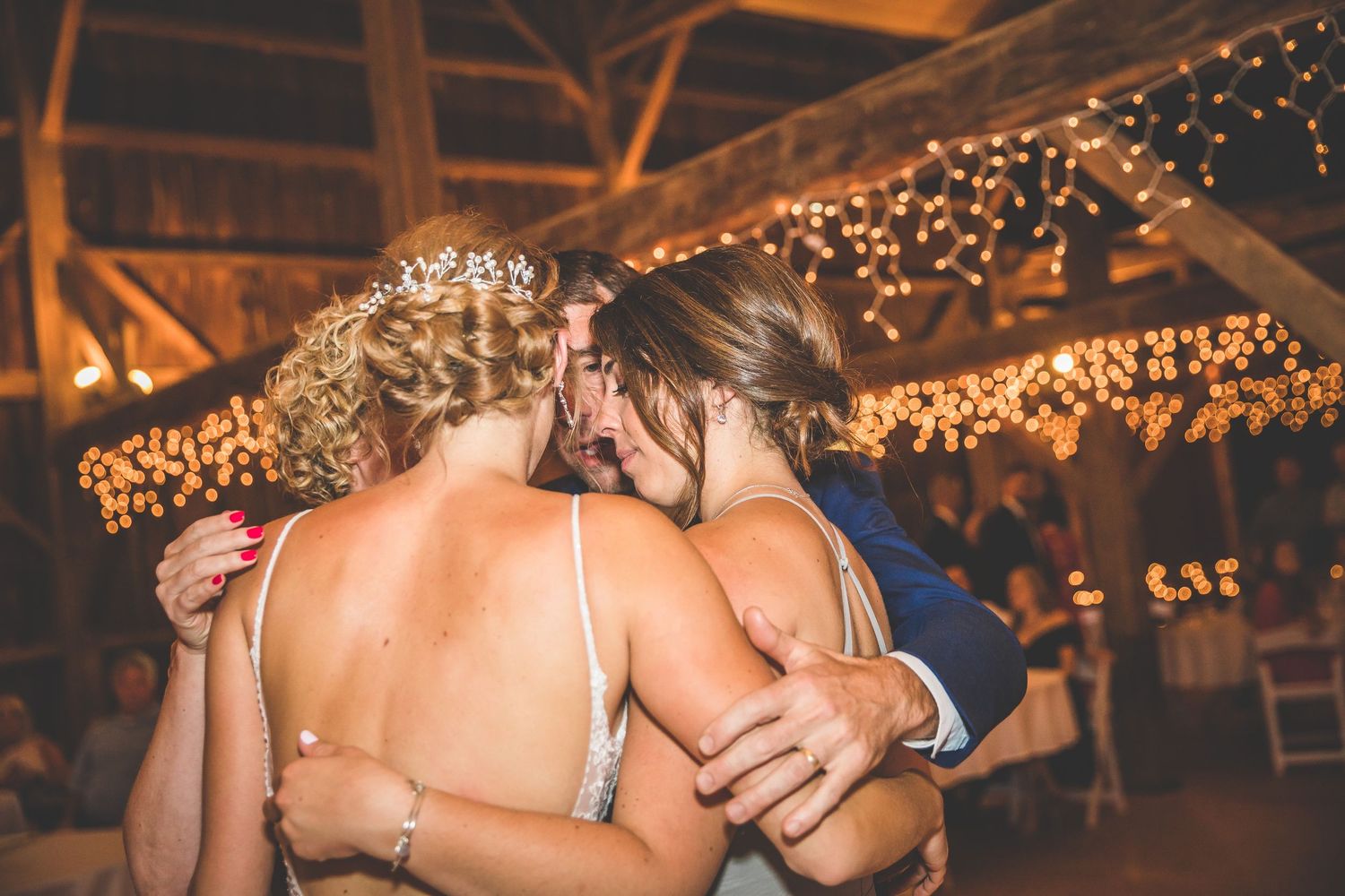 Romantic barn wedding celebration with twinkle lights strung across wooden rafters.