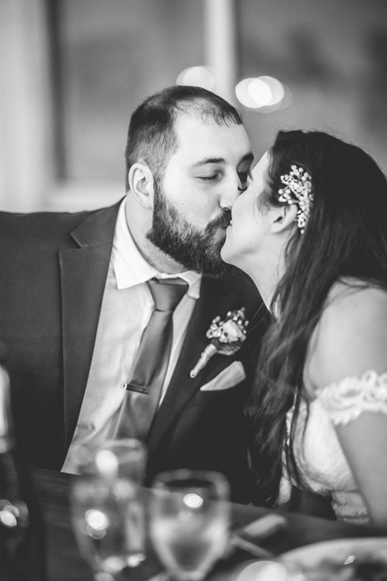 Black and white wedding photos showing romantic kisses between newlyweds during their reception celebration.
