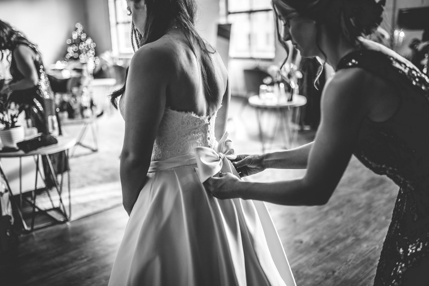 Black and white photo showing final bridal preparations in a sunlit room.
