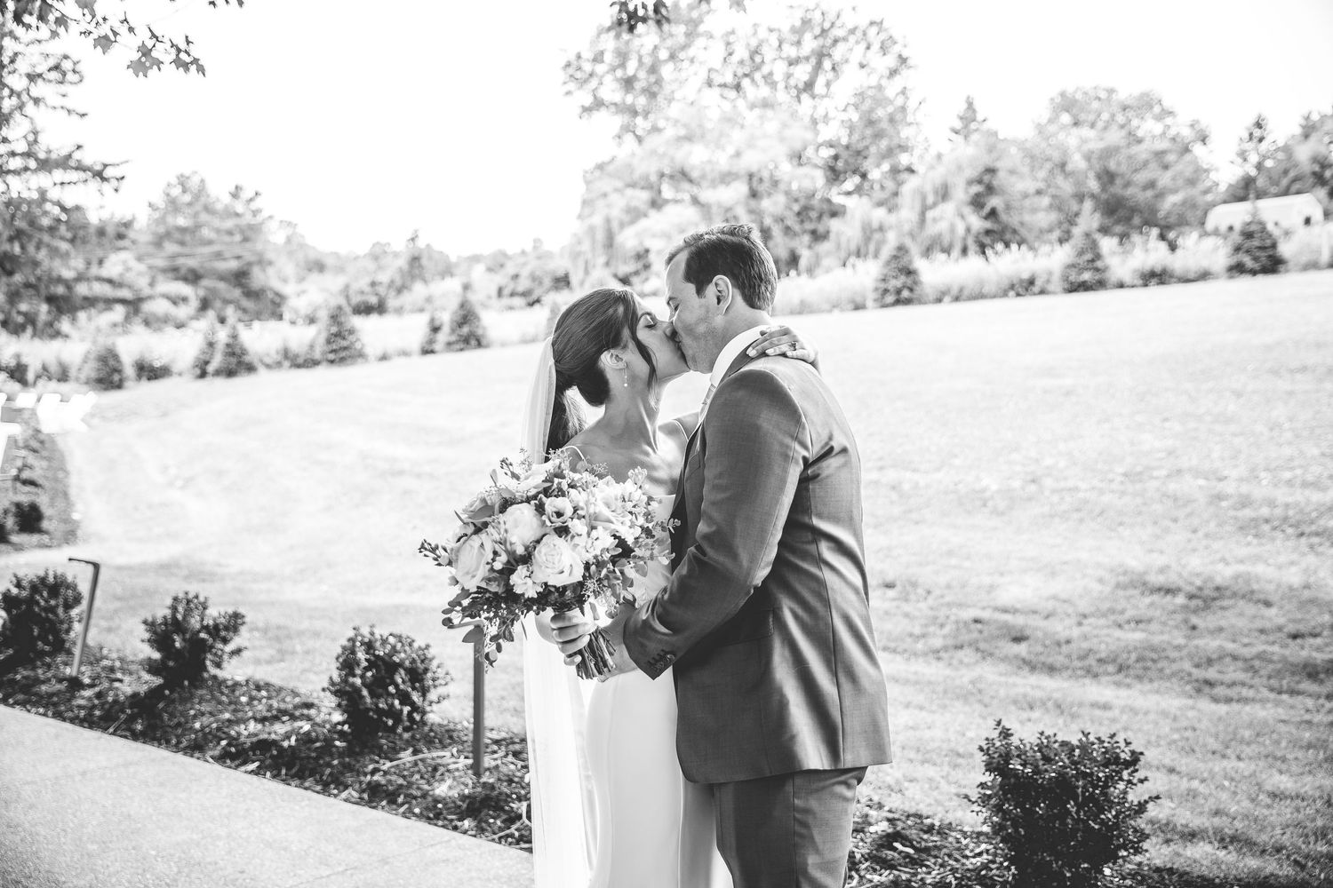 Wedding couple embraces in romantic outdoor garden setting with natural lighting.