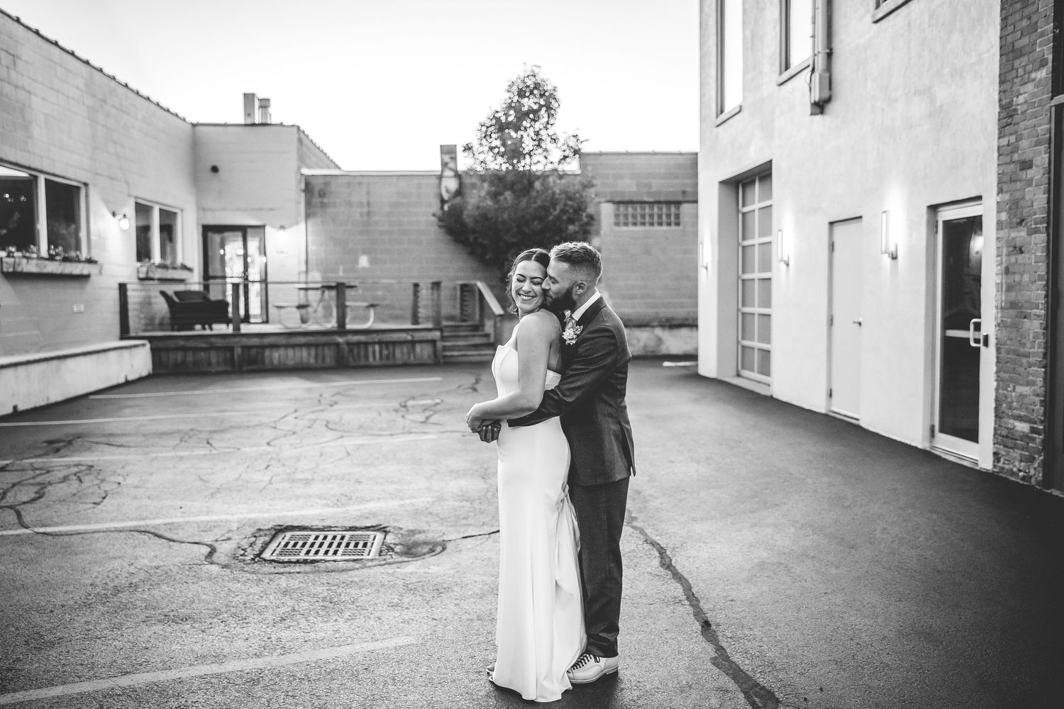 Black and white outdoor portrait of couple embracing in urban setting.