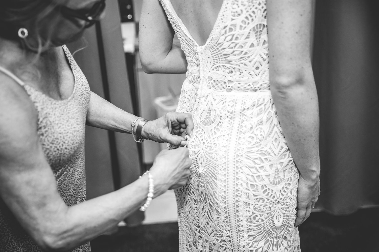 Close-up details of intricate lace and beading on white wedding dress.
