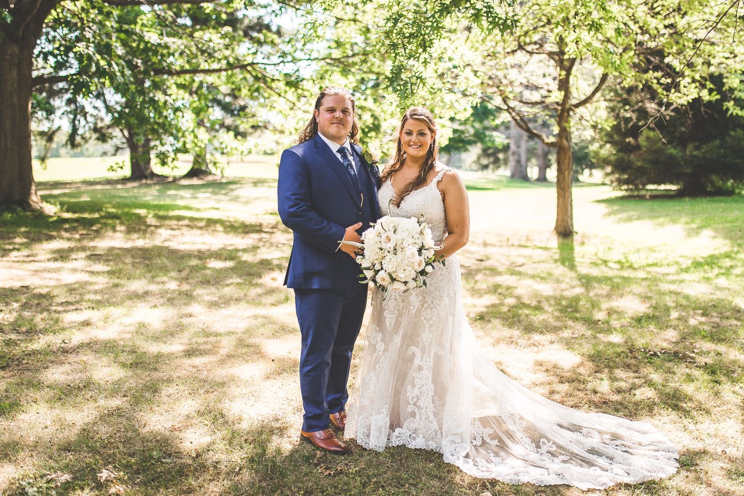 Newlyweds stroll together on a tree-lined pathway during their wedding photoshoot.