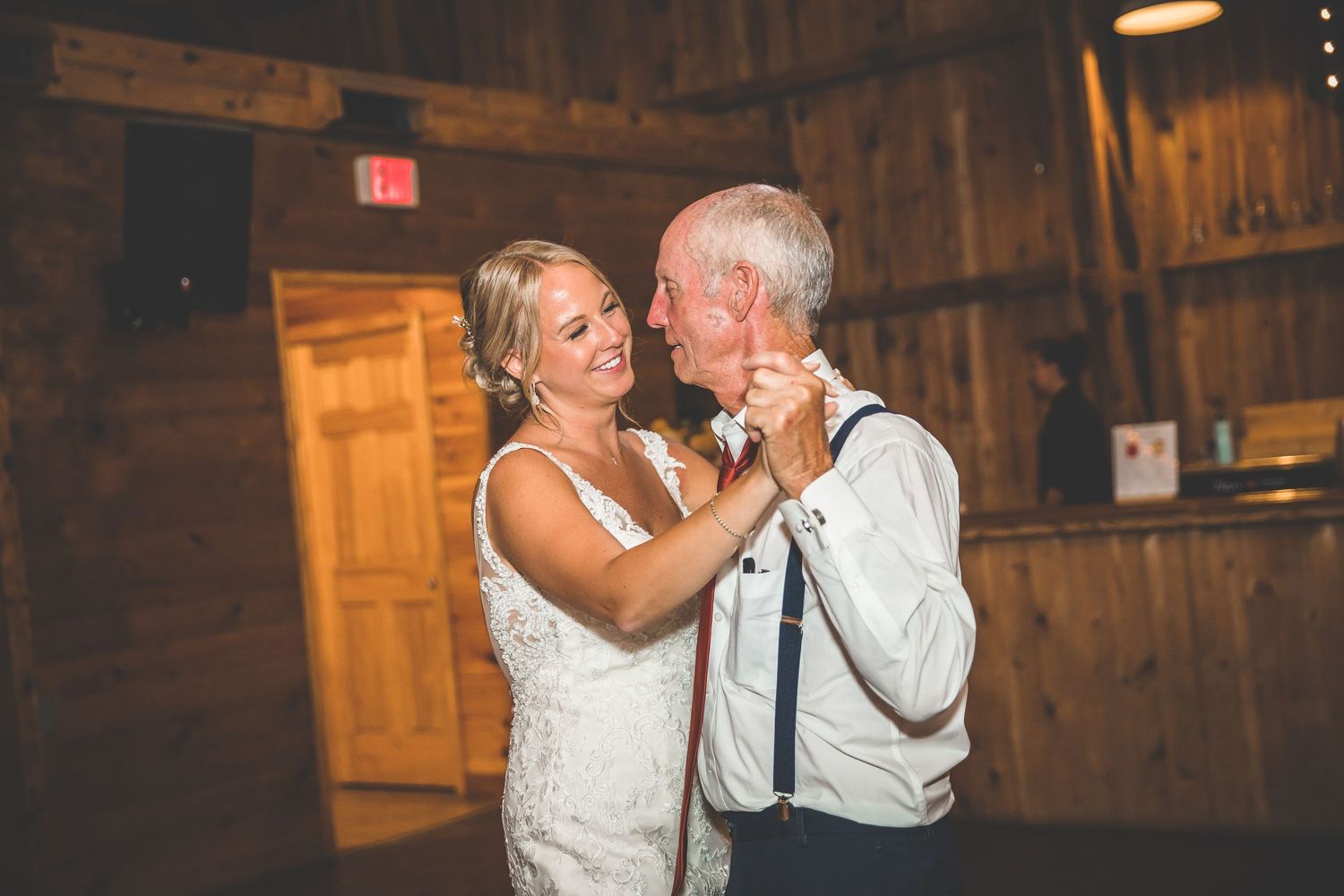 Wedding guests dancing and celebrating in a beautifully lit rustic barn setting.