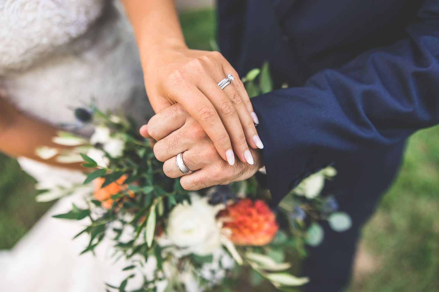Close-up detail of wedding rings and floral arrangements during ceremony.