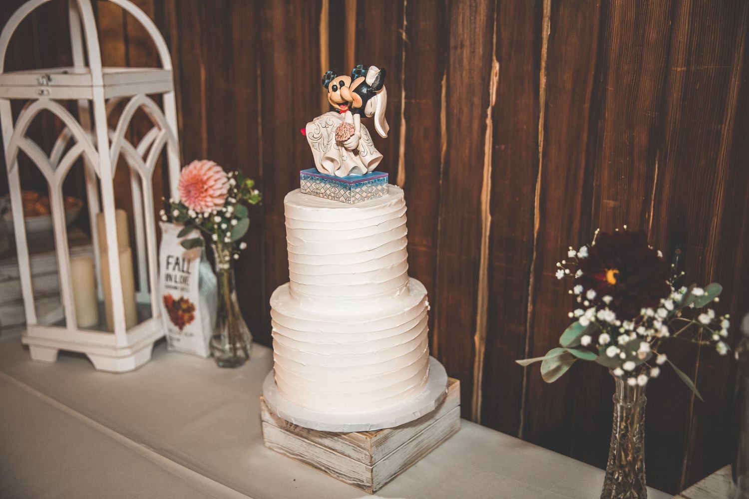 White wedding cakes with floral decorations displayed at rustic barn reception venue.