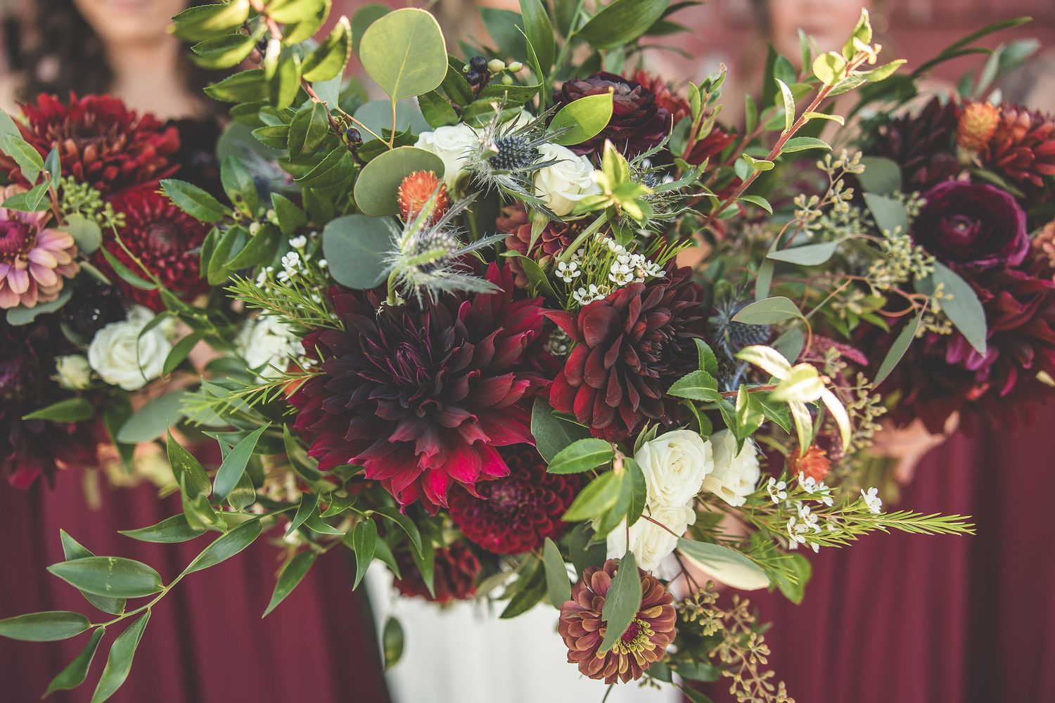 Close-up of burgundy and greenery wedding floral arrangements with rich deep tones.