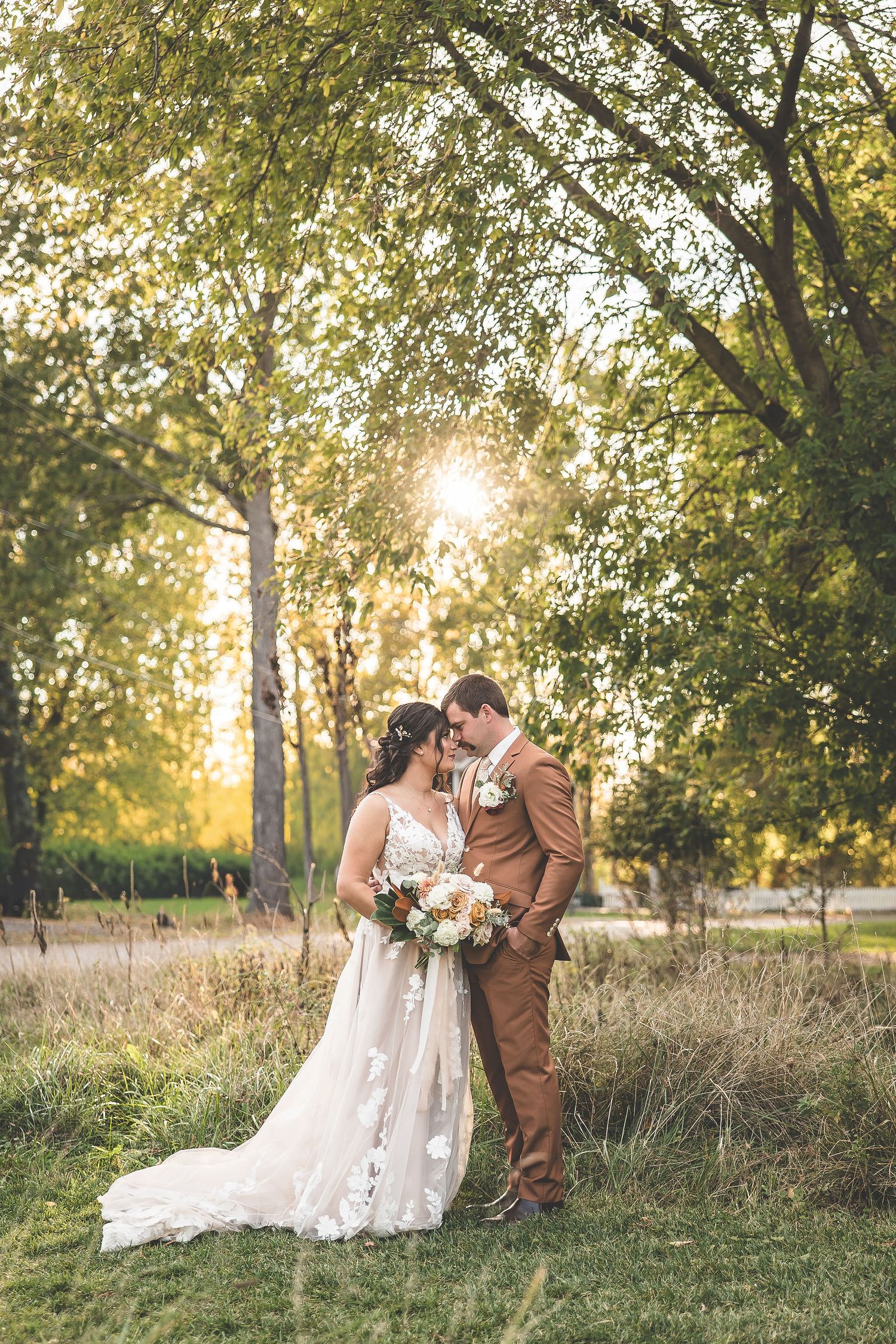 Newlyweds share intimate moments on grassy hillside during golden hour photo session.