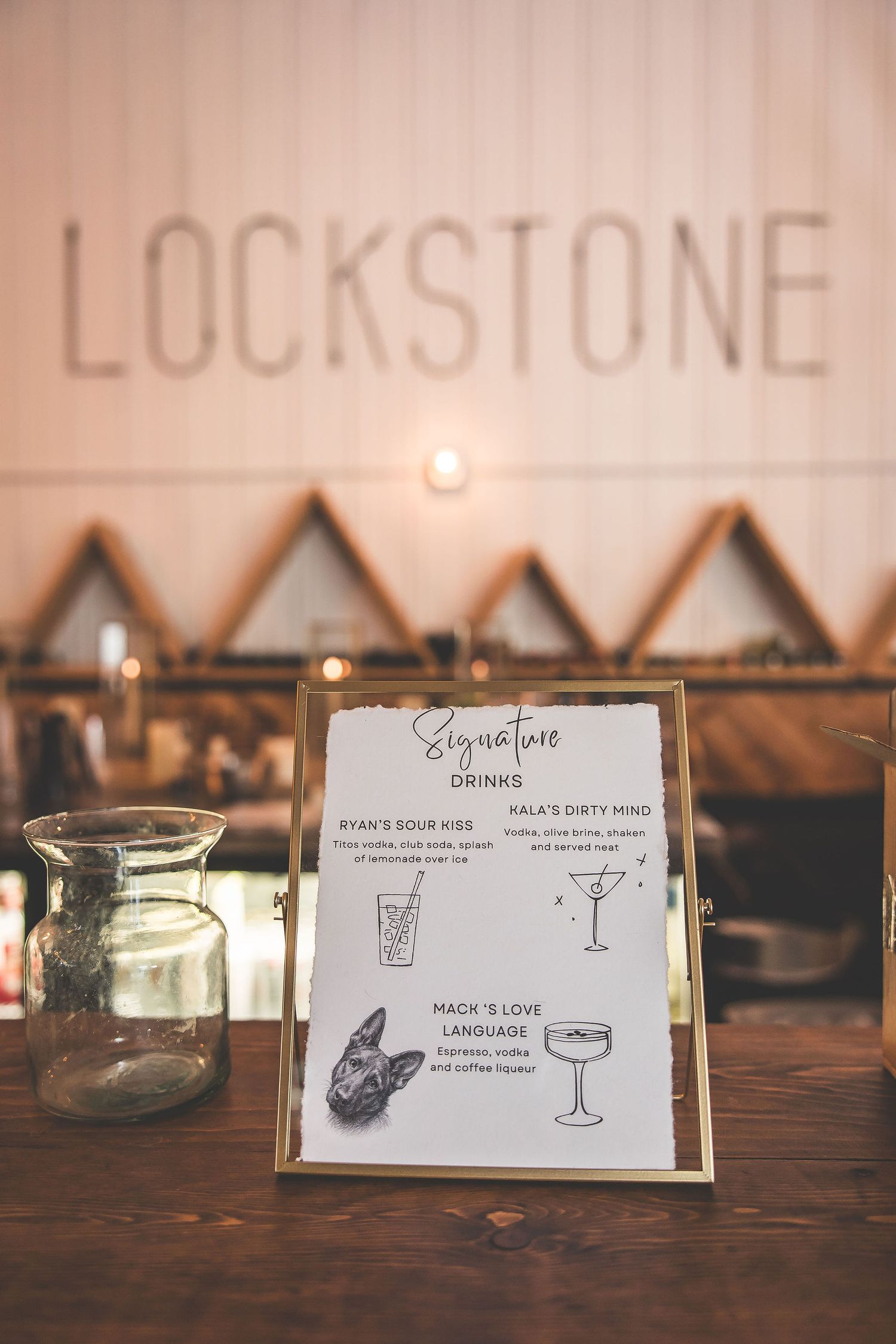 Wedding reception table settings with signature drink menu cards and candle holders.