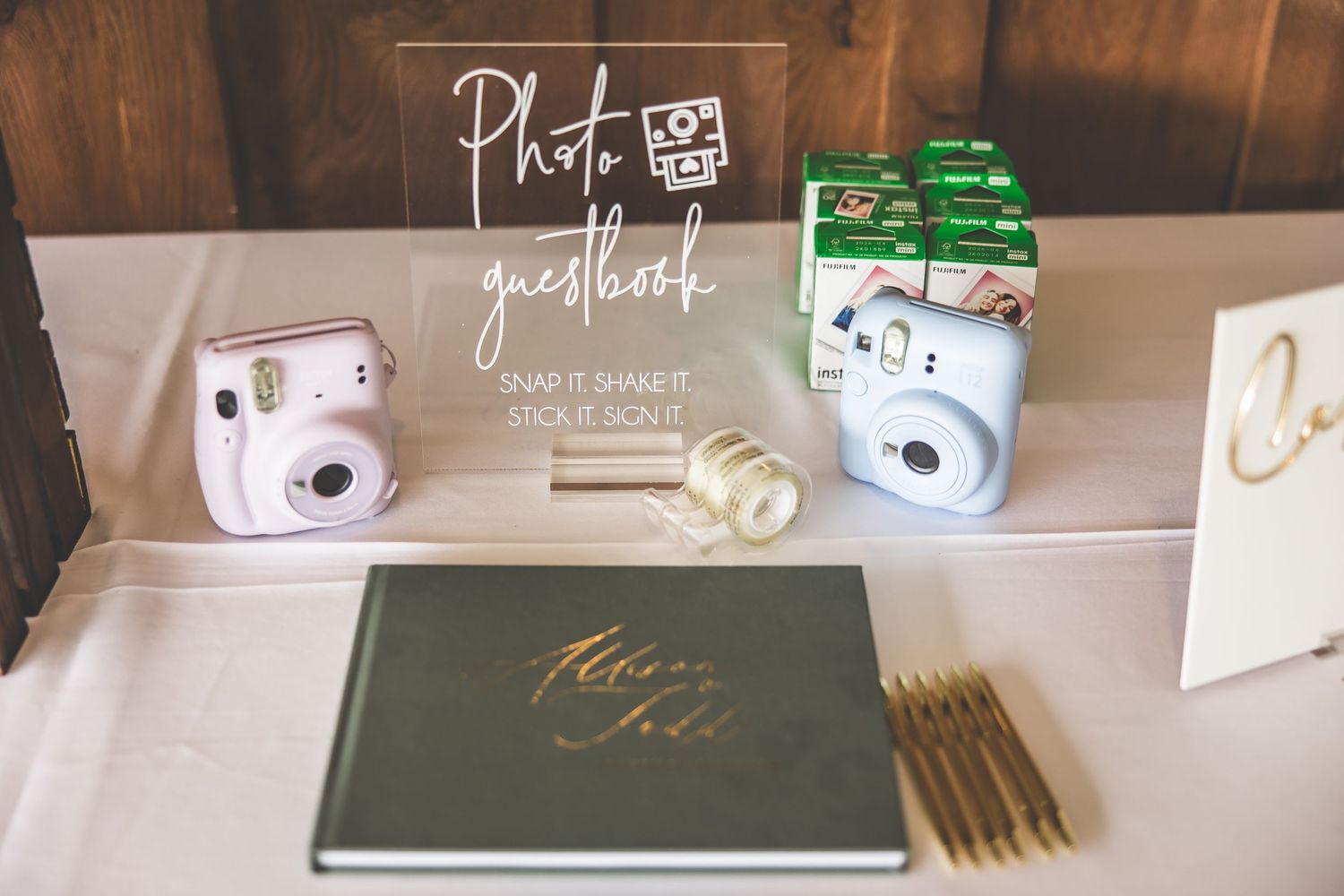 Wedding detail shots of photography equipment and signage on a neutral surface.
