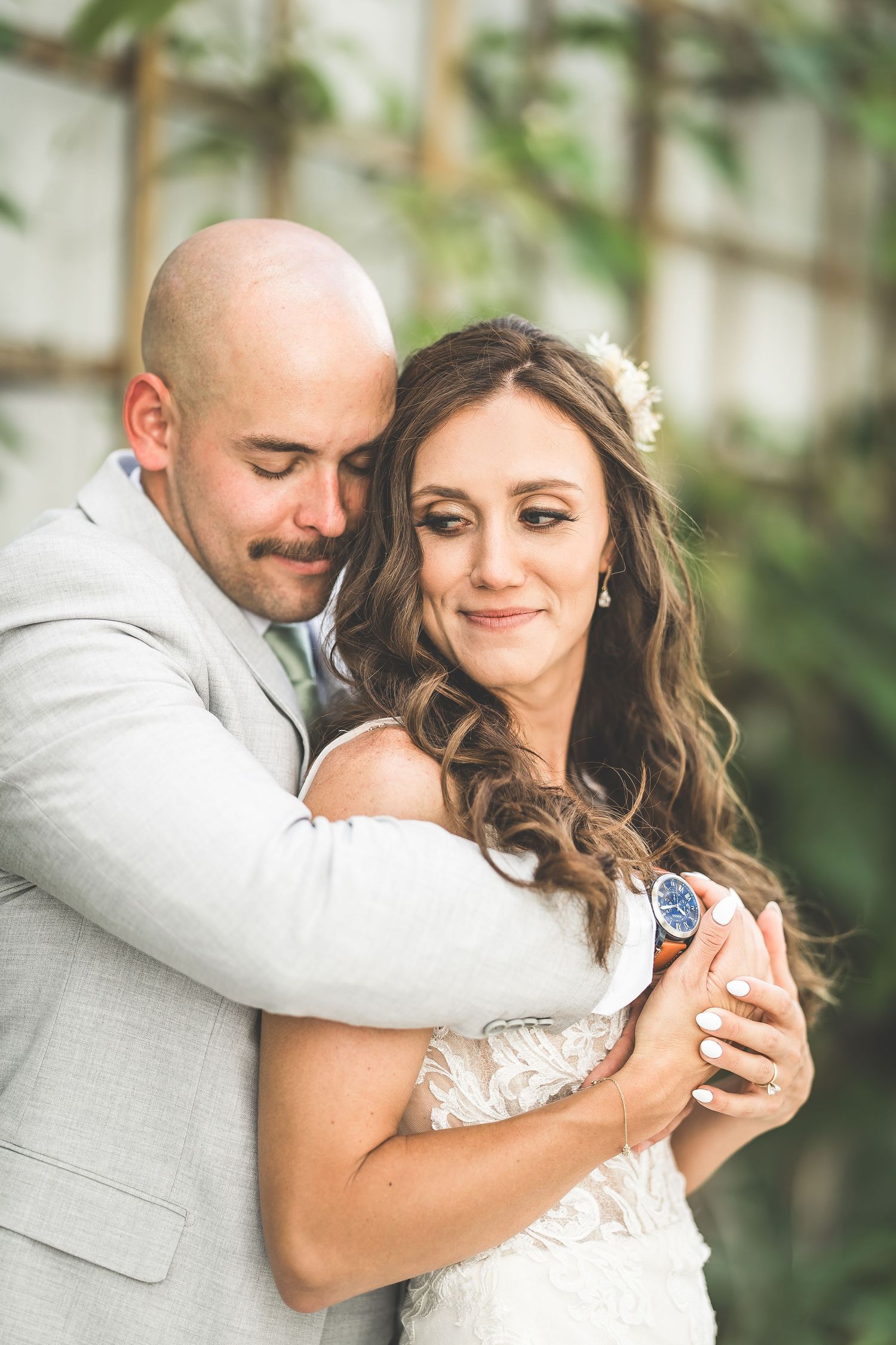 A tender embrace between newlyweds surrounded by greenery and natural light.