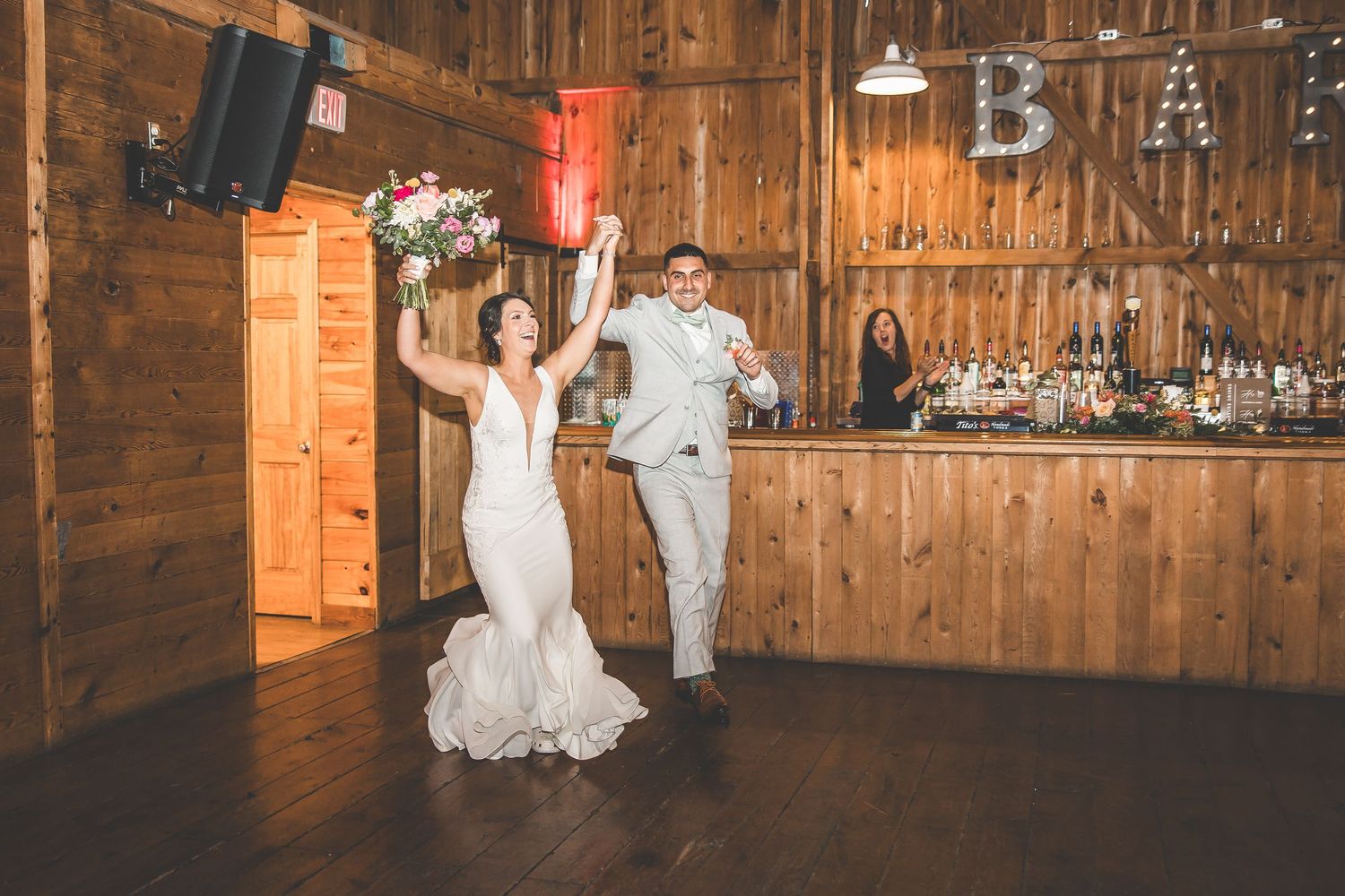 Wedding reception venue inside rustic barn with wooden walls and ambient lighting.