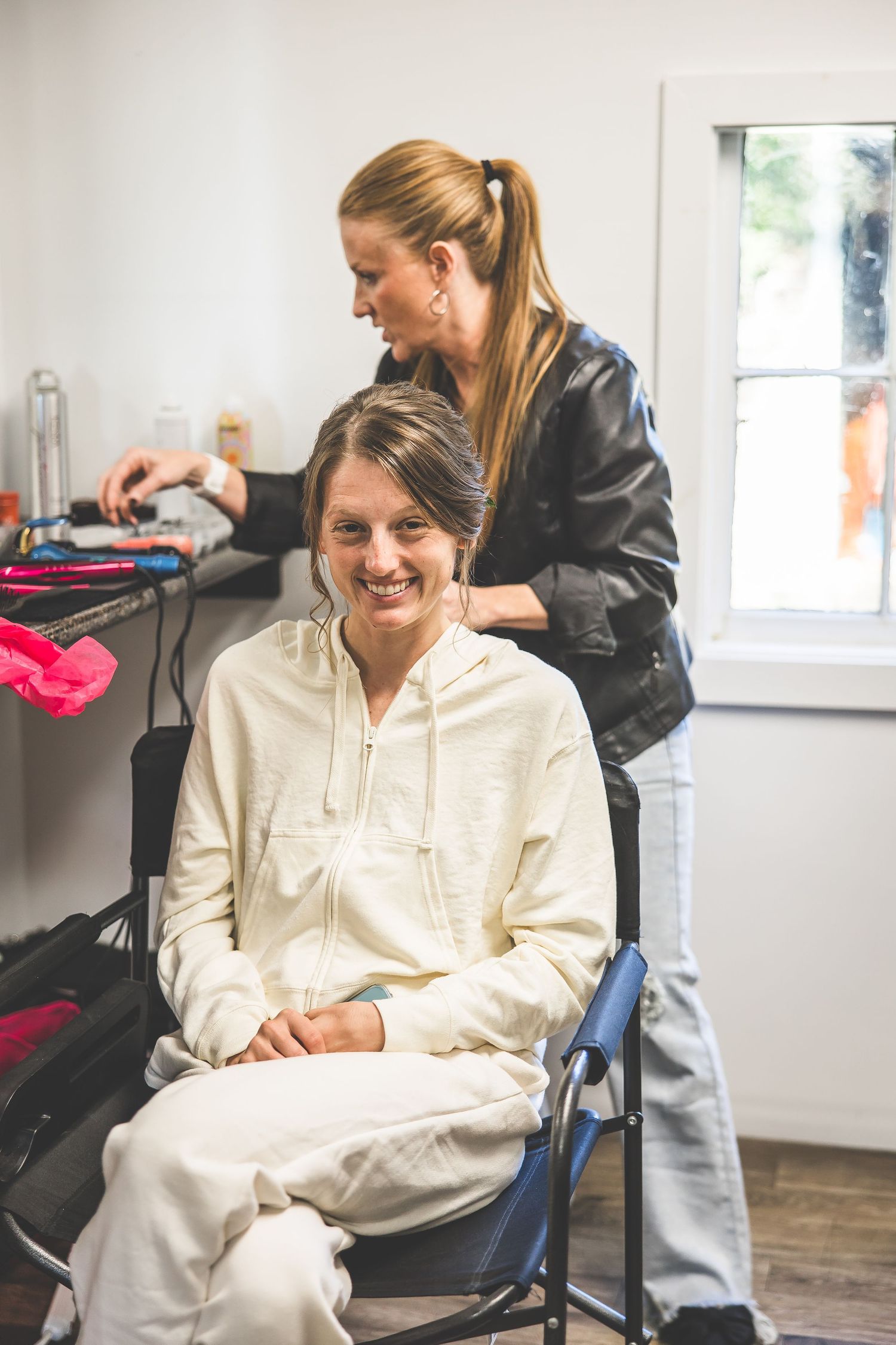 Getting ready scene in a bright room with styling preparations underway.