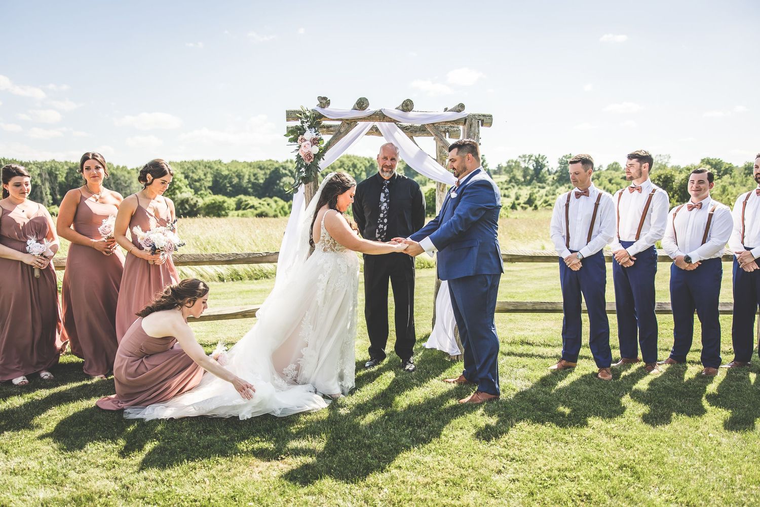 Wedding celebration in a sunny field with guests gathered for outdoor festivities.