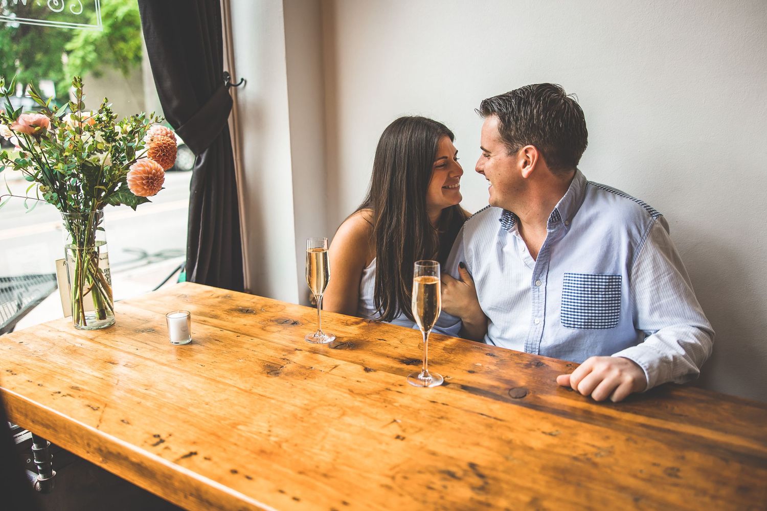 Couple sitting at wooden table during intimate restaurant gathering.