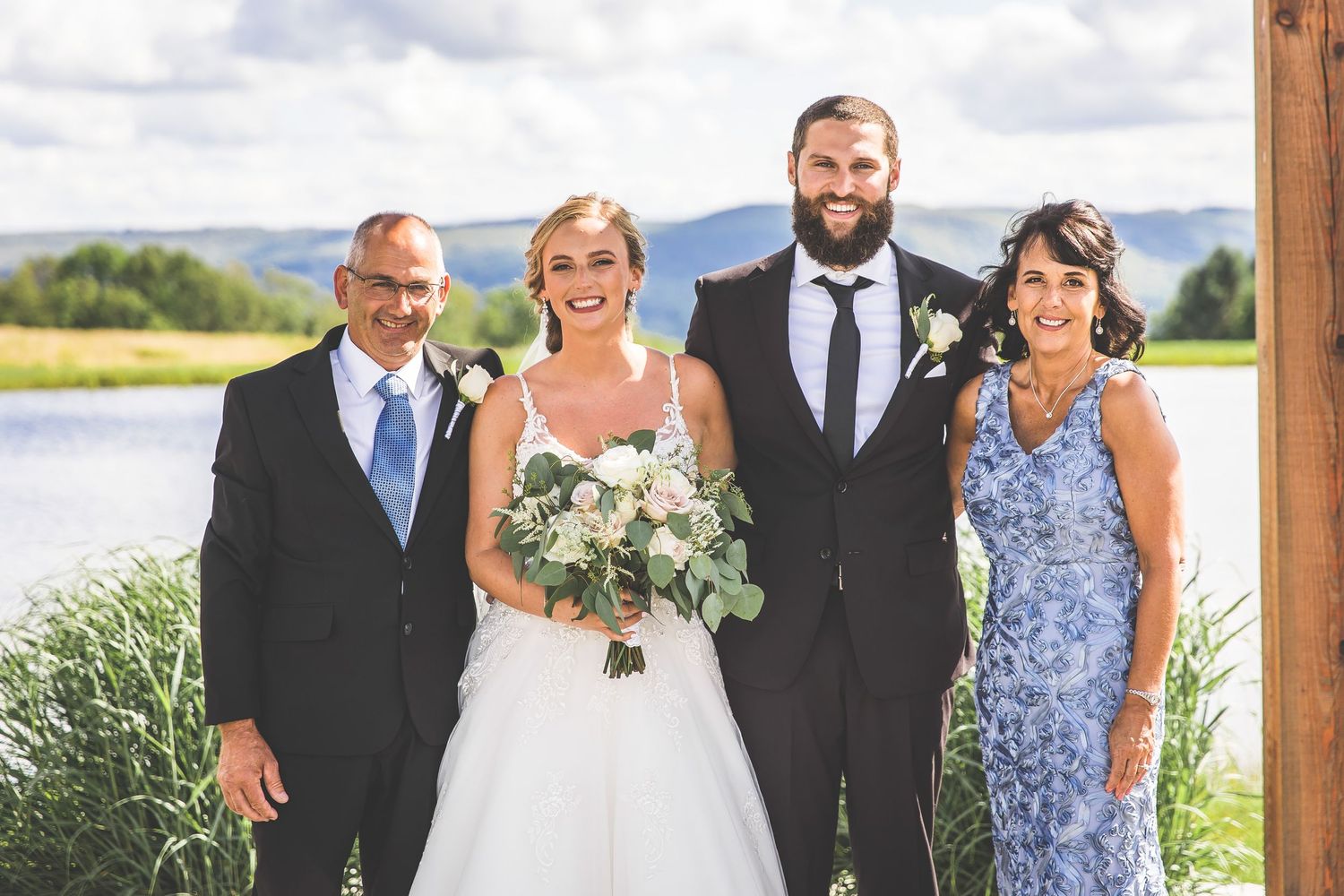A group portrait taken at a wedding with a lake and mountains in the background.