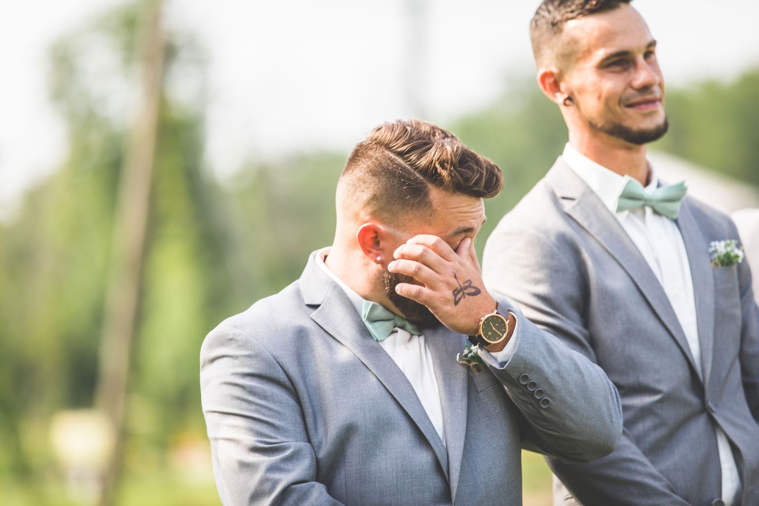 Groomsmen in gray suits sharing a lighthearted moment during wedding photos.