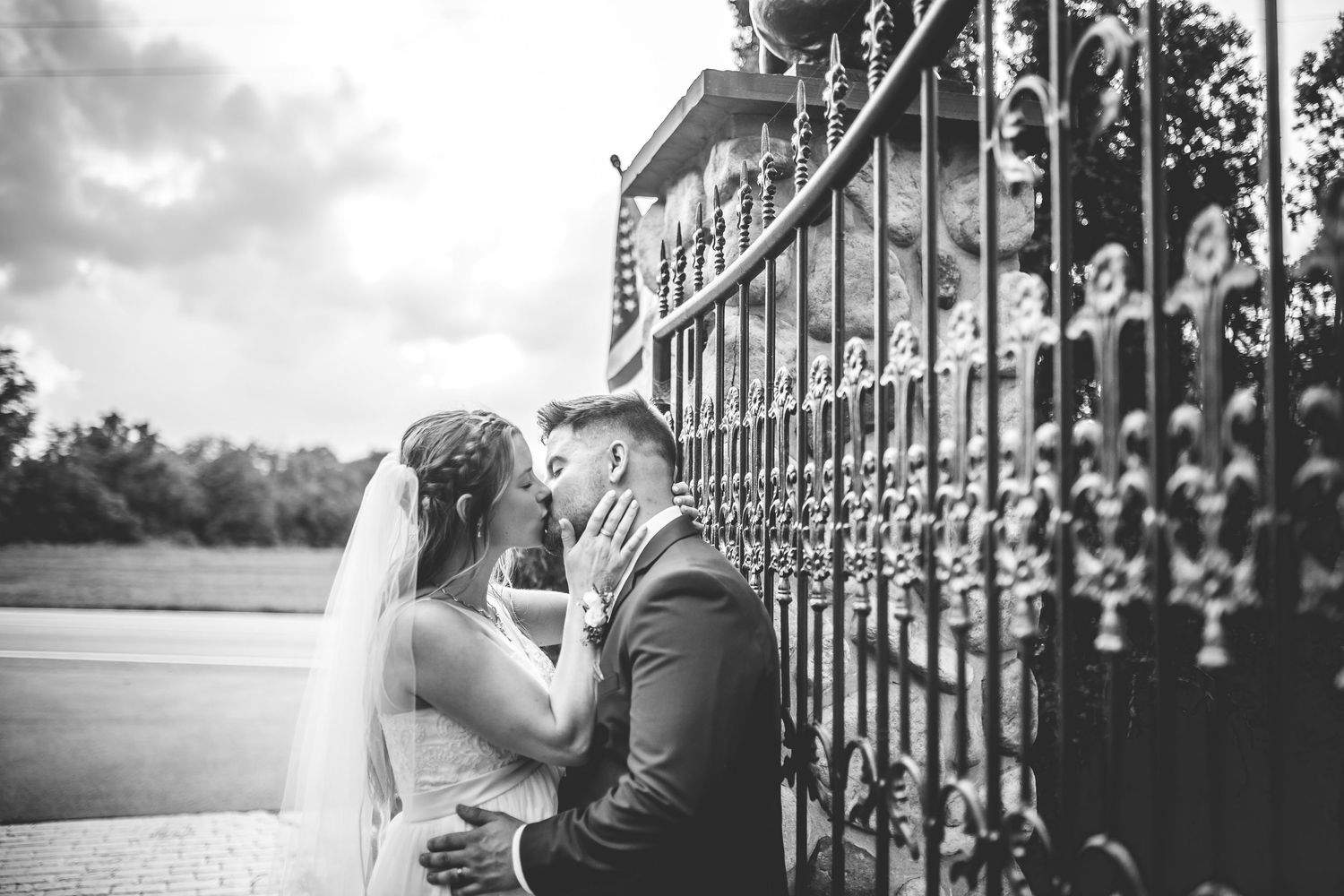 Black and white wedding portrait against ornate iron gates.